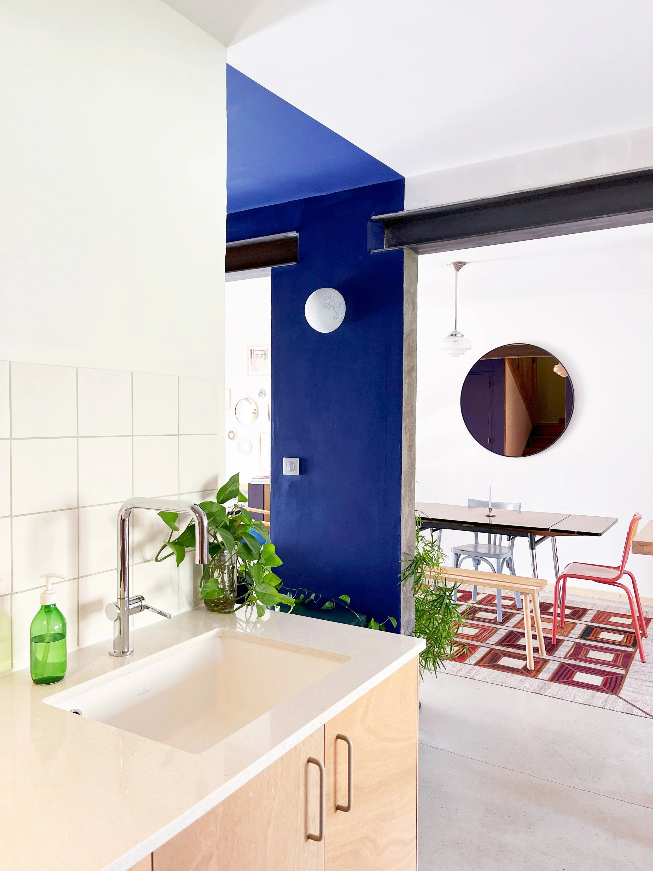 Cuisine en bois brut contreplaqué avec crédence graphique et joint vert, salle à manger avec comptoir en bois massif.