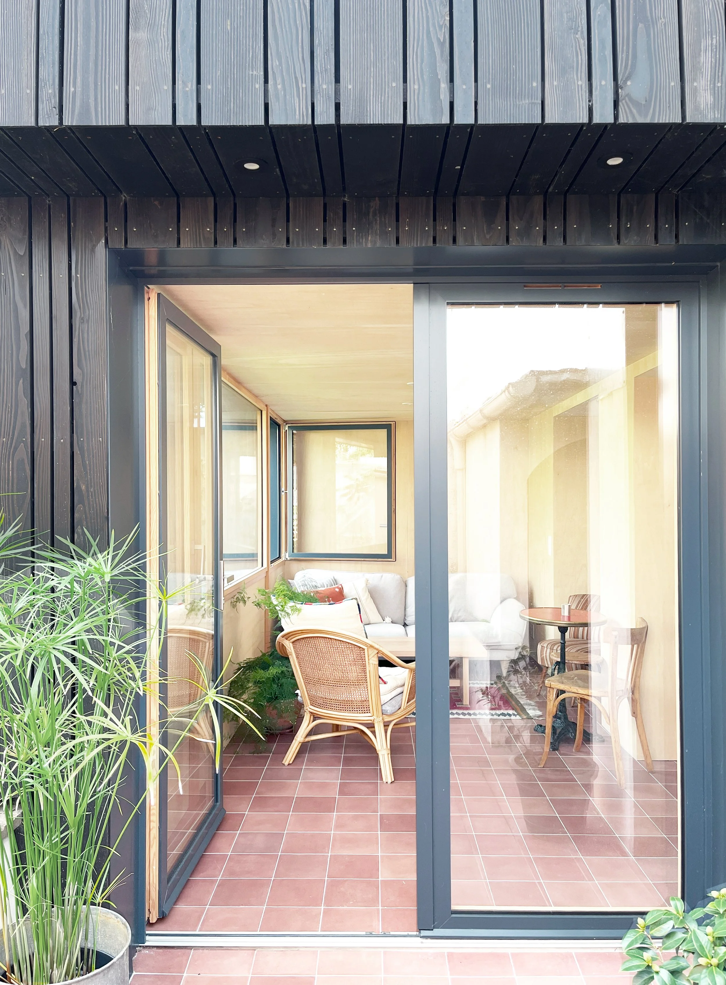 Extension en bardage bois brûlé avec sol continu intérieur-extérieur et architecture épurée