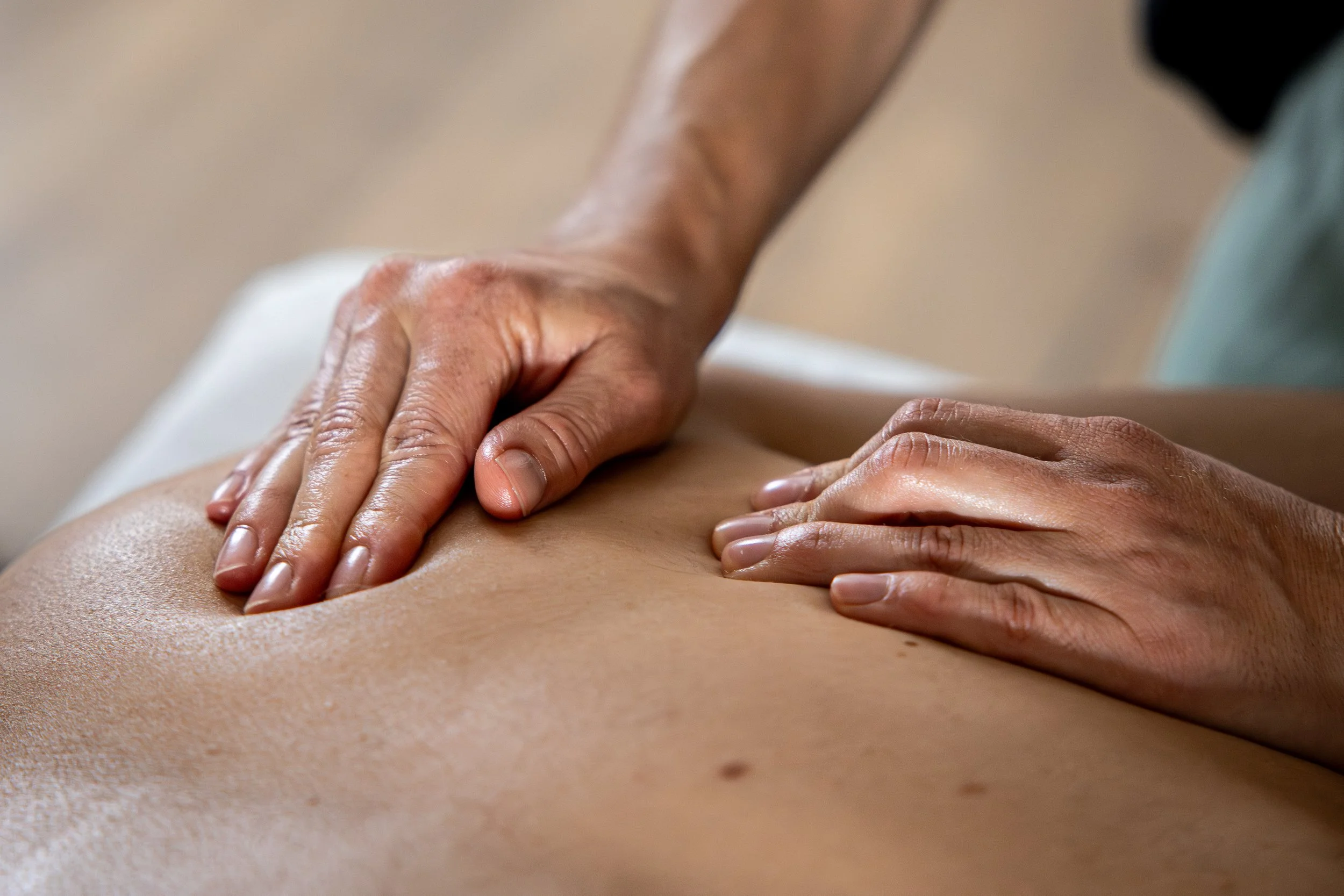 massage du dos, les mains de la masseuse sont en gros plan et réalisent des pressions sur le dos.