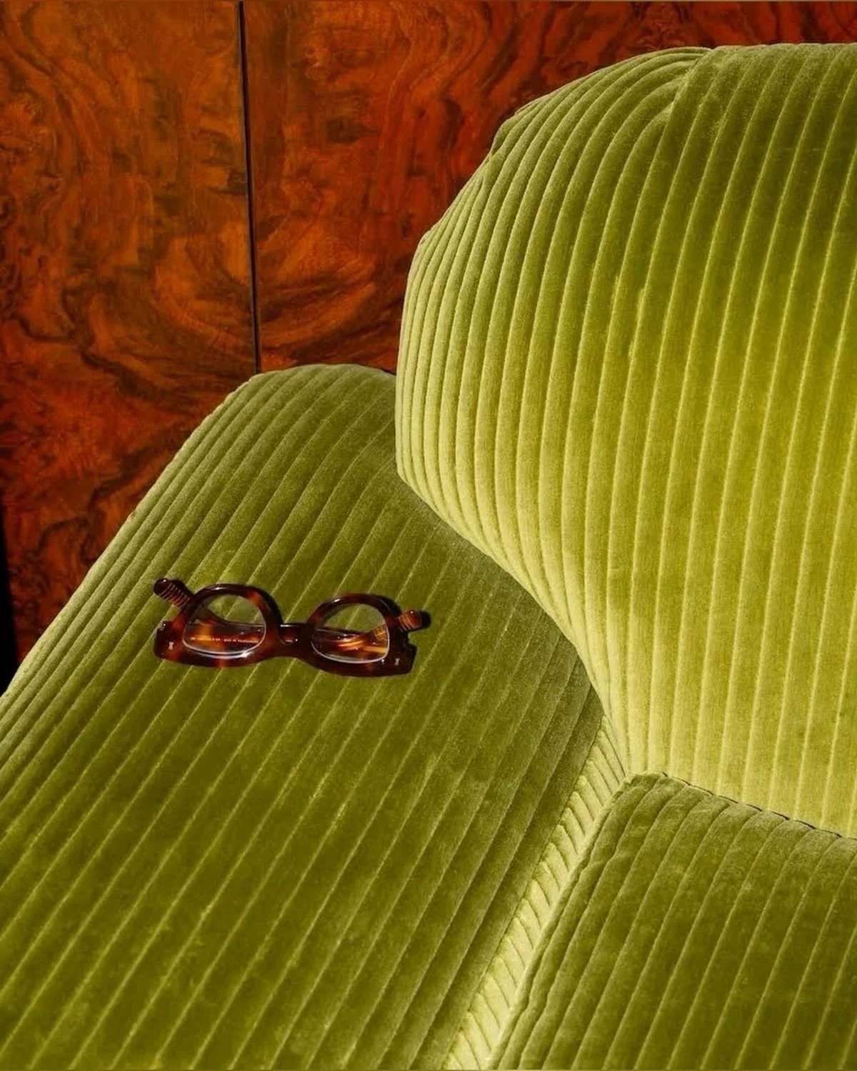 A corduroy olive green armchair against warm burl wood. Cosy and inviting.