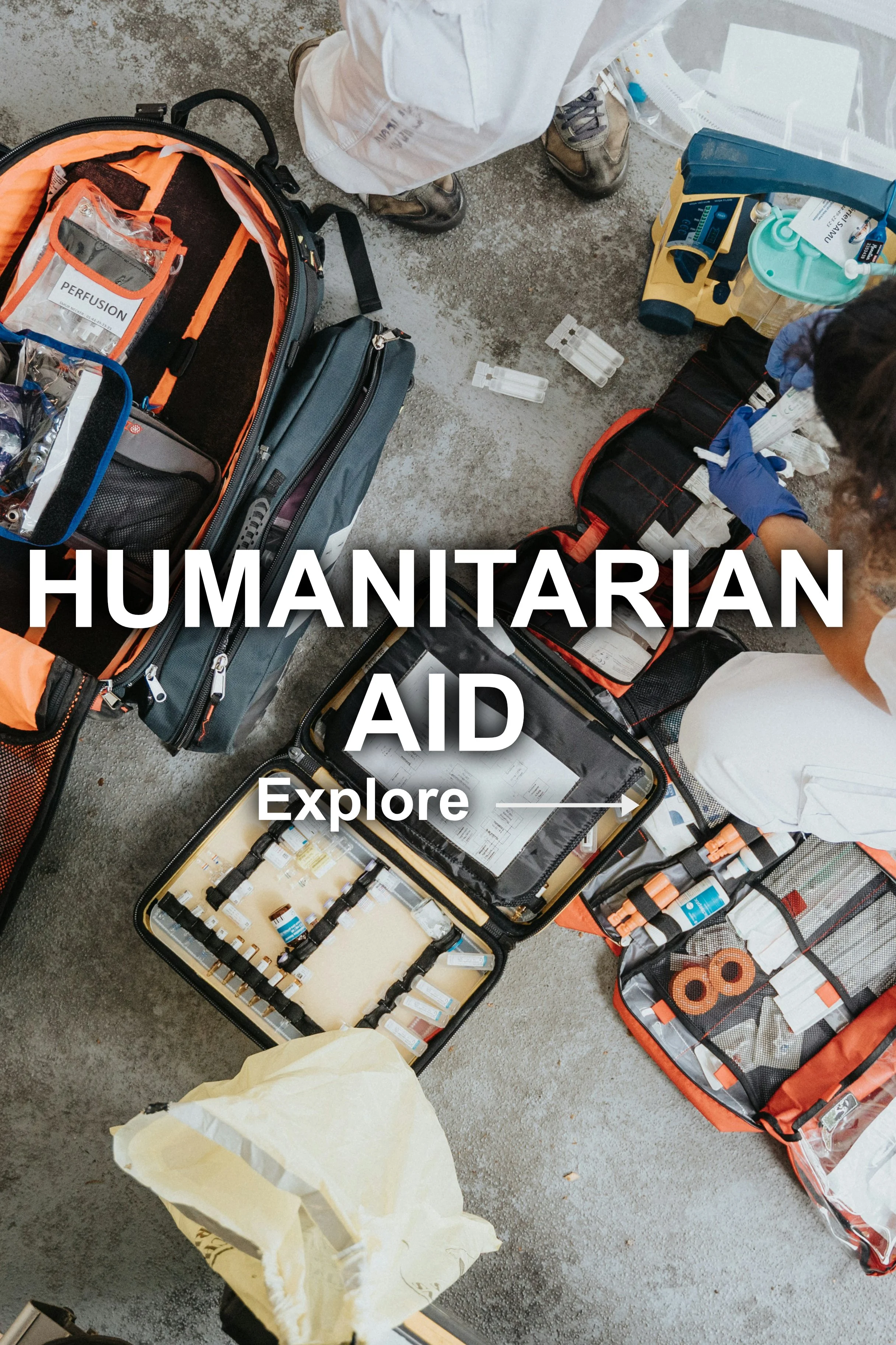 Medical supplies and equipment for a humanitarian aid effort on a concrete floor, including patches, medical tools, and backpacks, with people organizing them.