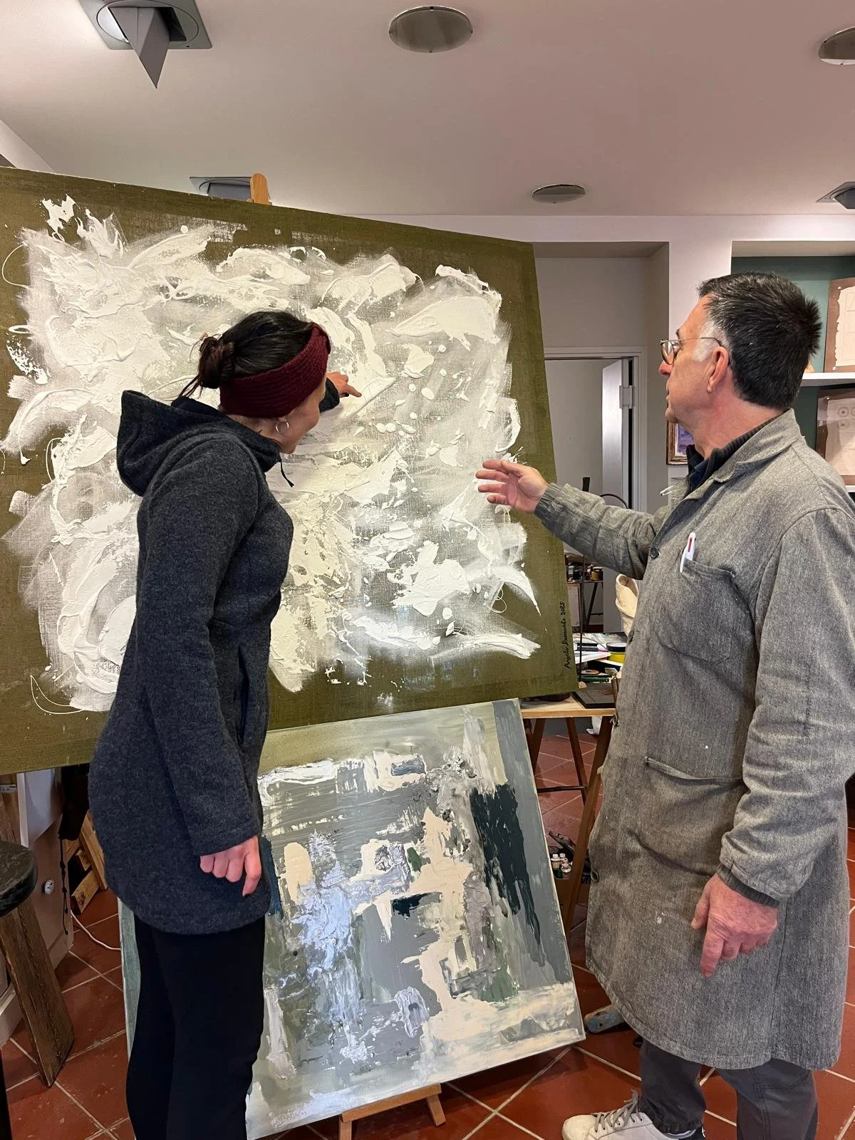 Un artista e un uomo discutono durante un processo di pittura astratta su due tele in uno studio artistico.