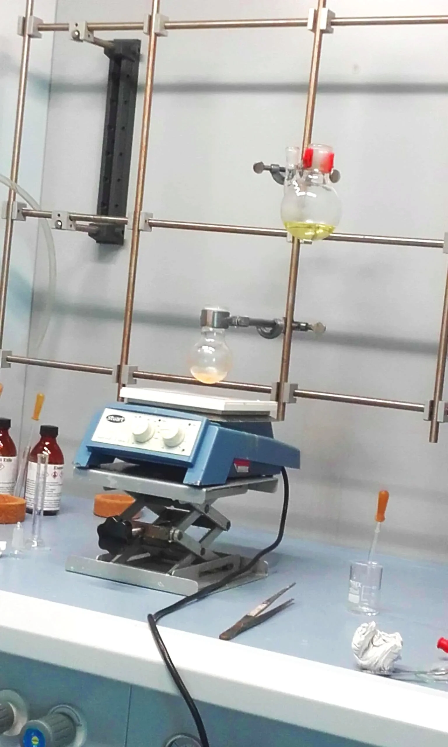 Setup di laboratorio chimico con apparecchiature, fiale e reagenti su banco da lavoro.
