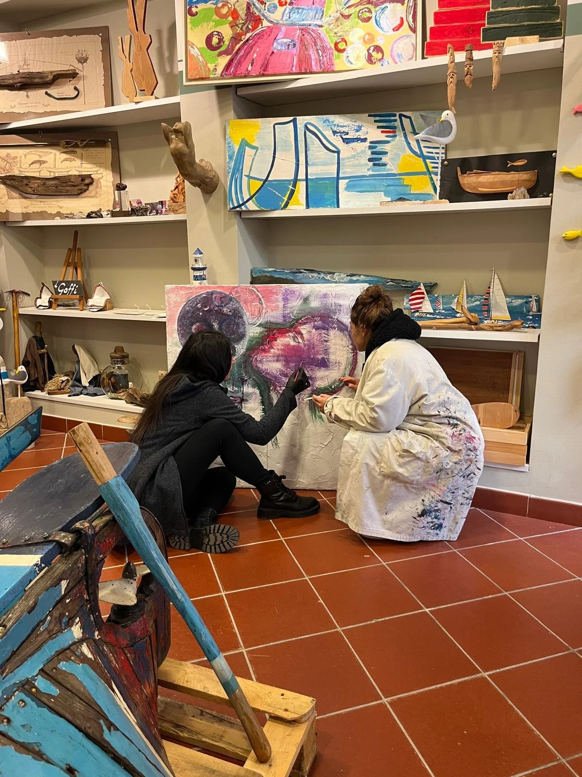 Due persone che dipingono un quadro astratto in un atelier, circondate da opere d'arte e oggetti artistici