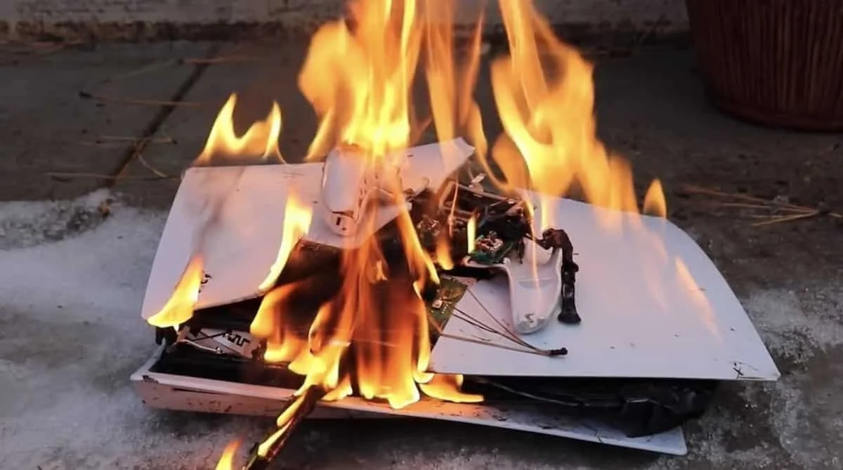 A PlayStation gaming console on fire, flames engulfing its surface.