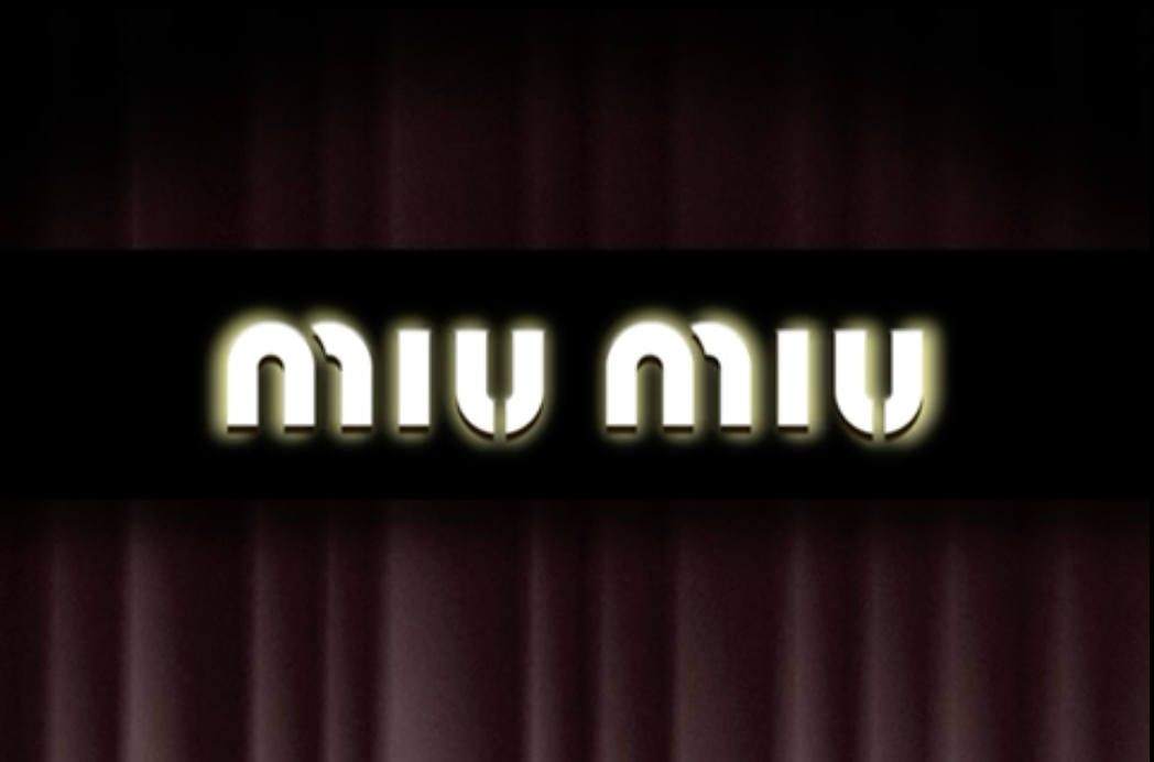 Illuminated black sign with the words "Miu Miu" in stylized font, against a dark background.