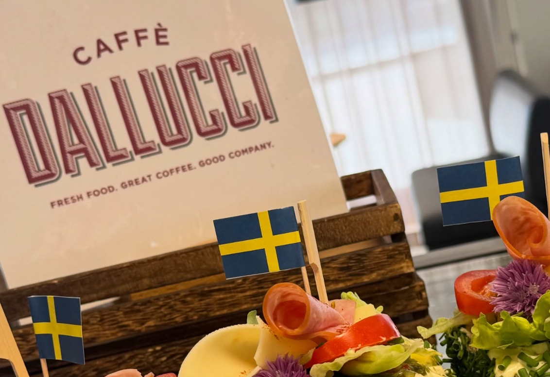 Smörgåstårtbitar med svenska flaggan i. I bakgrunden Caffè Dalluccis logotype på en skylt