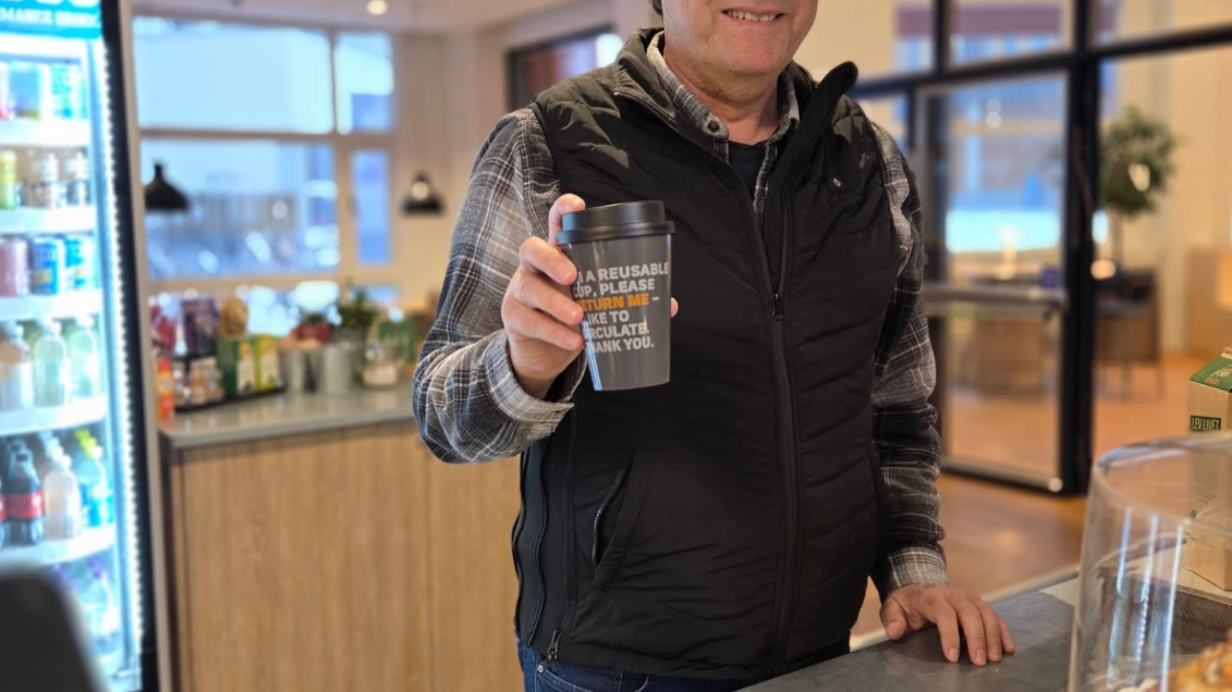 Kund på ett café som håller i en flergångsmugg från Panter
