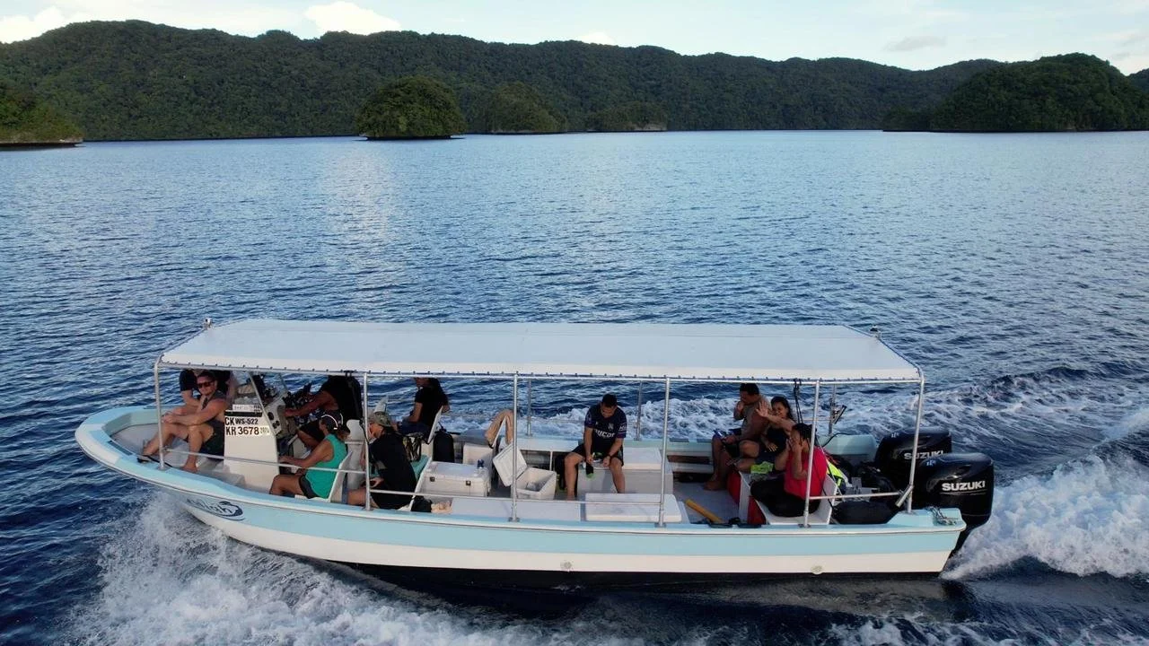 A group of people enjoying a boat ride on a lake with lush green hills in the background.