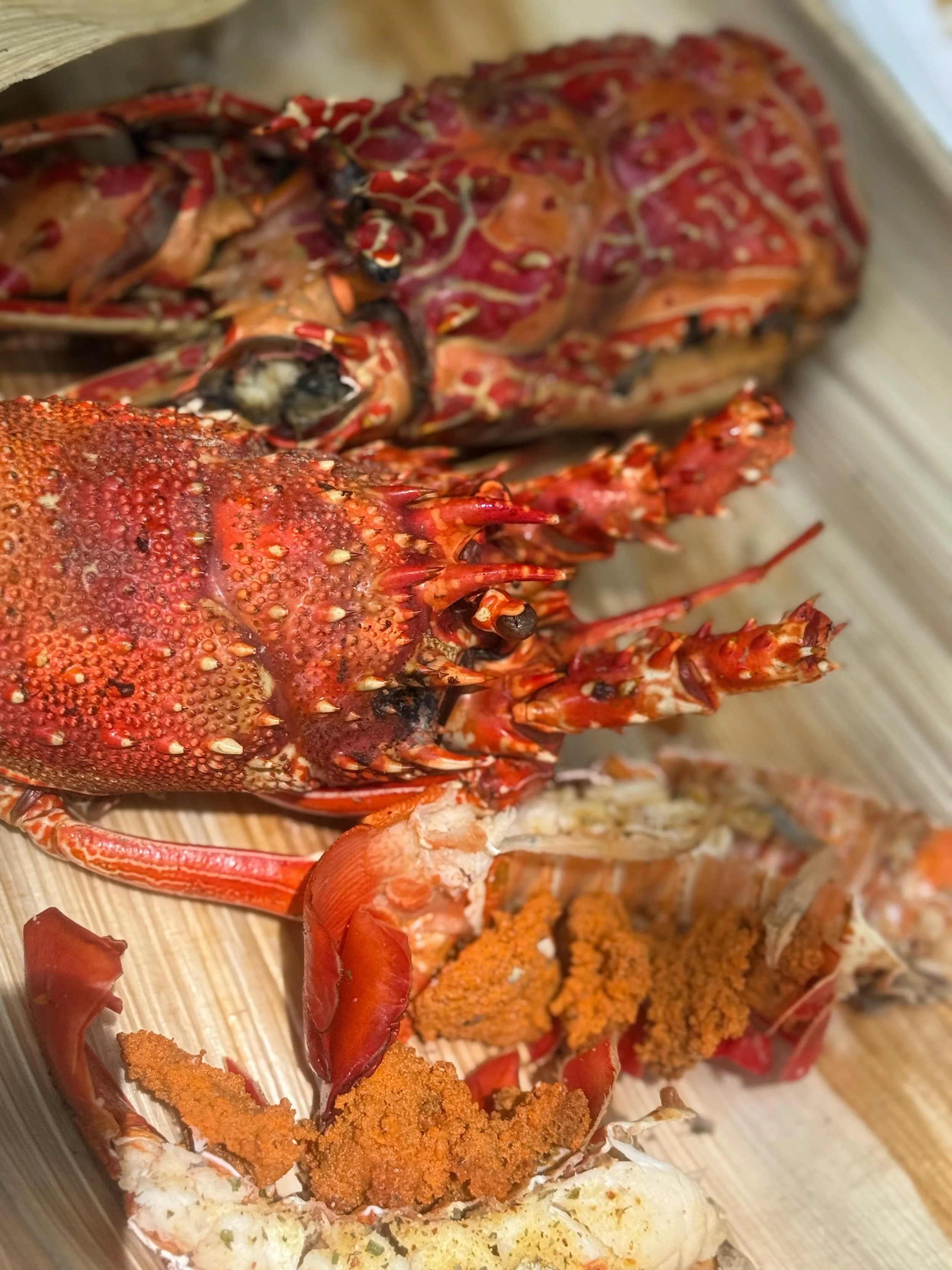 Freshly cooked lobsters with bright red shells, placed on a wooden surface.