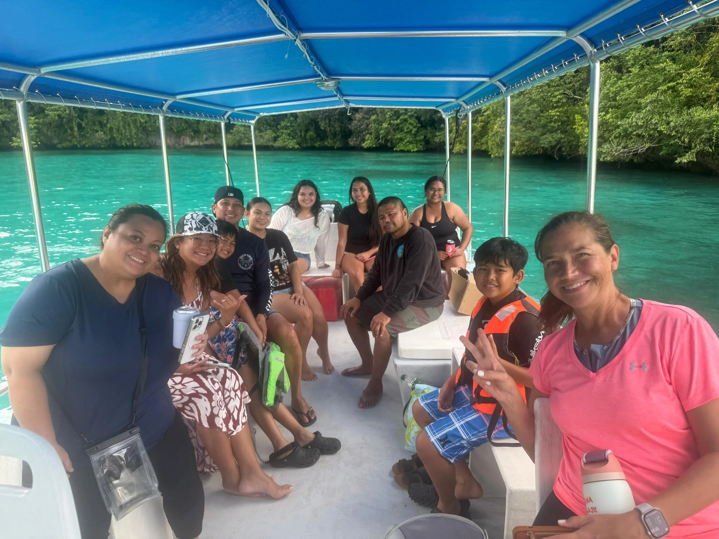 Group of people on a boat with turquoise water and green trees in the background.