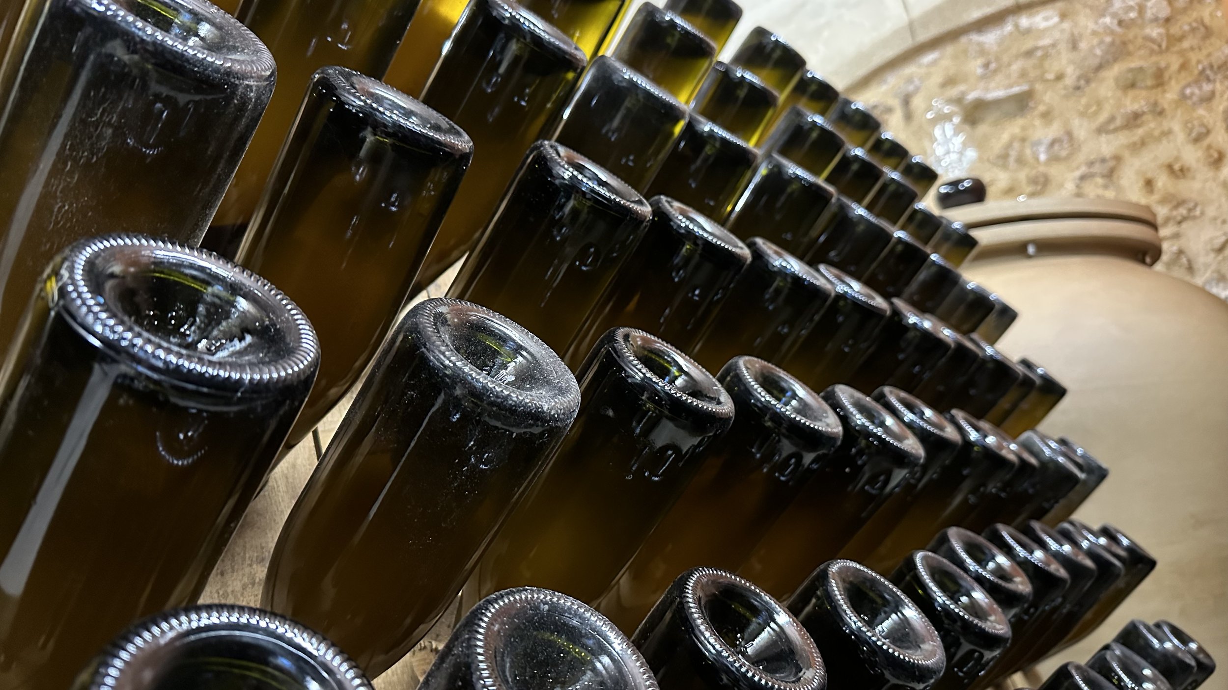 Bouteilles de vin stockées sur des étagères en bois, vues de dessus.