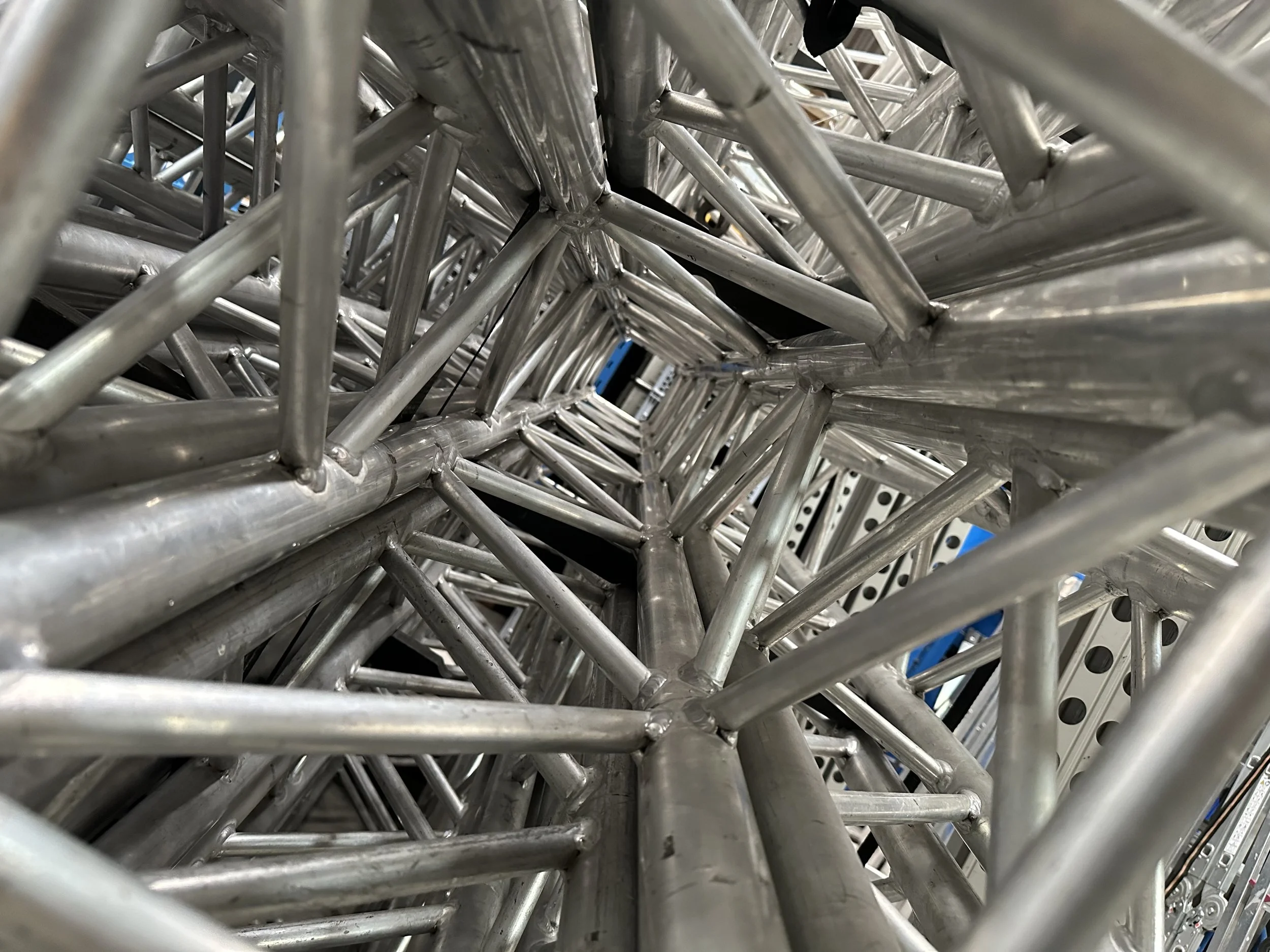 Close-up view of a metal truss structure with interconnected rods and joints.