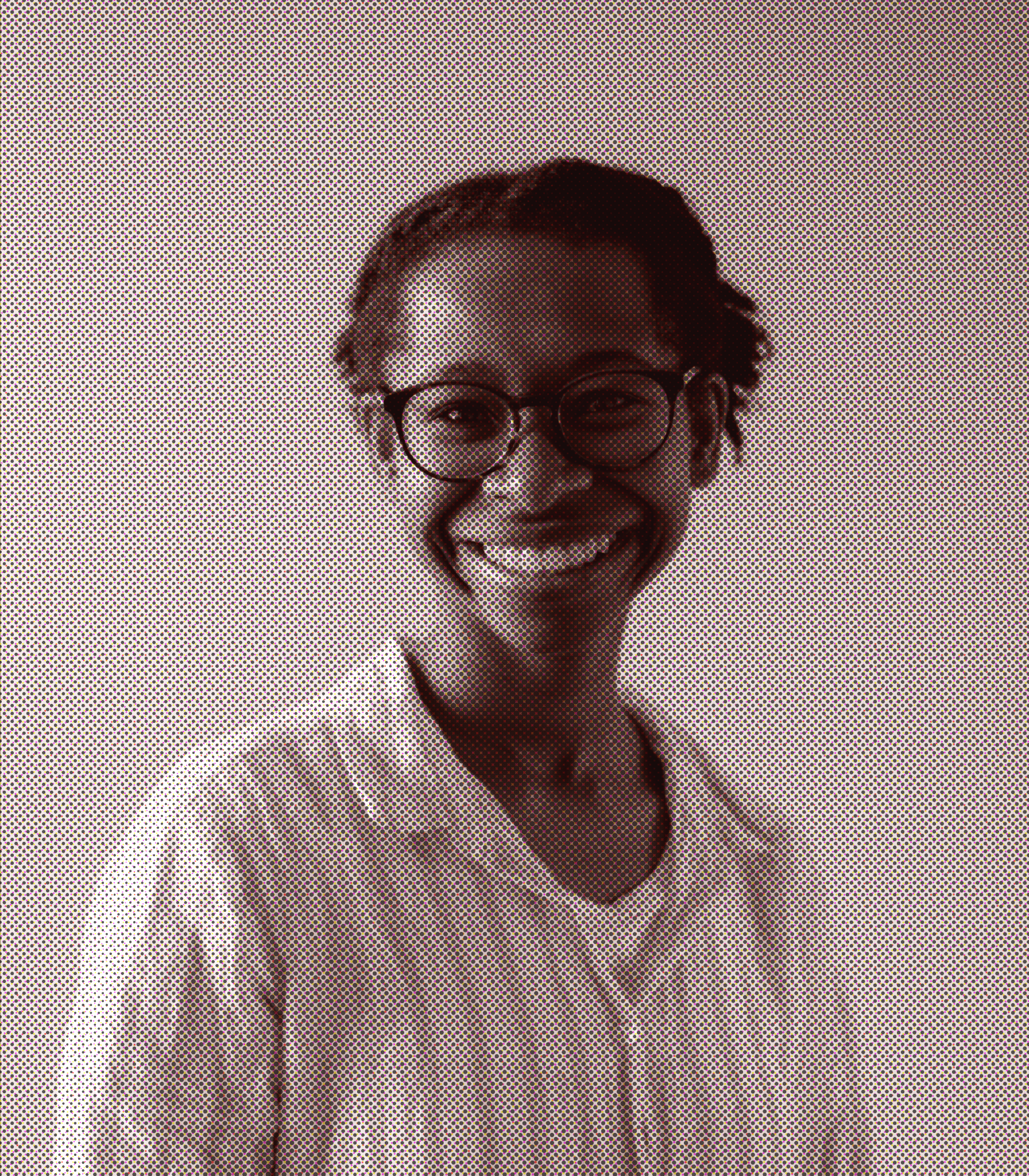 A portrait of a person wearing glasses, smiling, against a plain background.