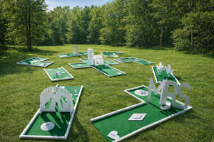 Miniature golf course with various holes and obstacles on a grassy field, surrounded by trees.