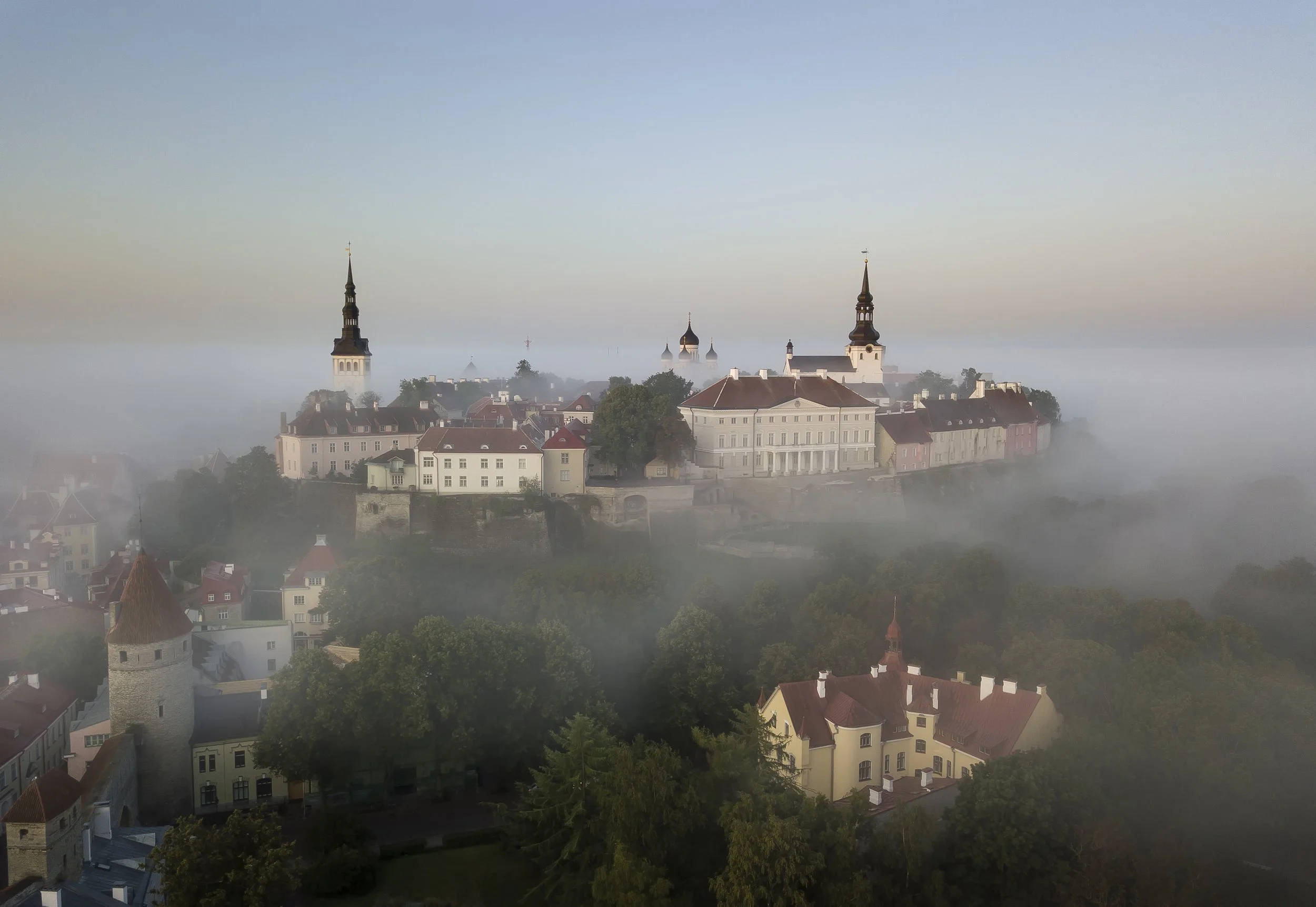 Historic city viewed from above shrouded in mist. All that can be seen is the spires and rooftops