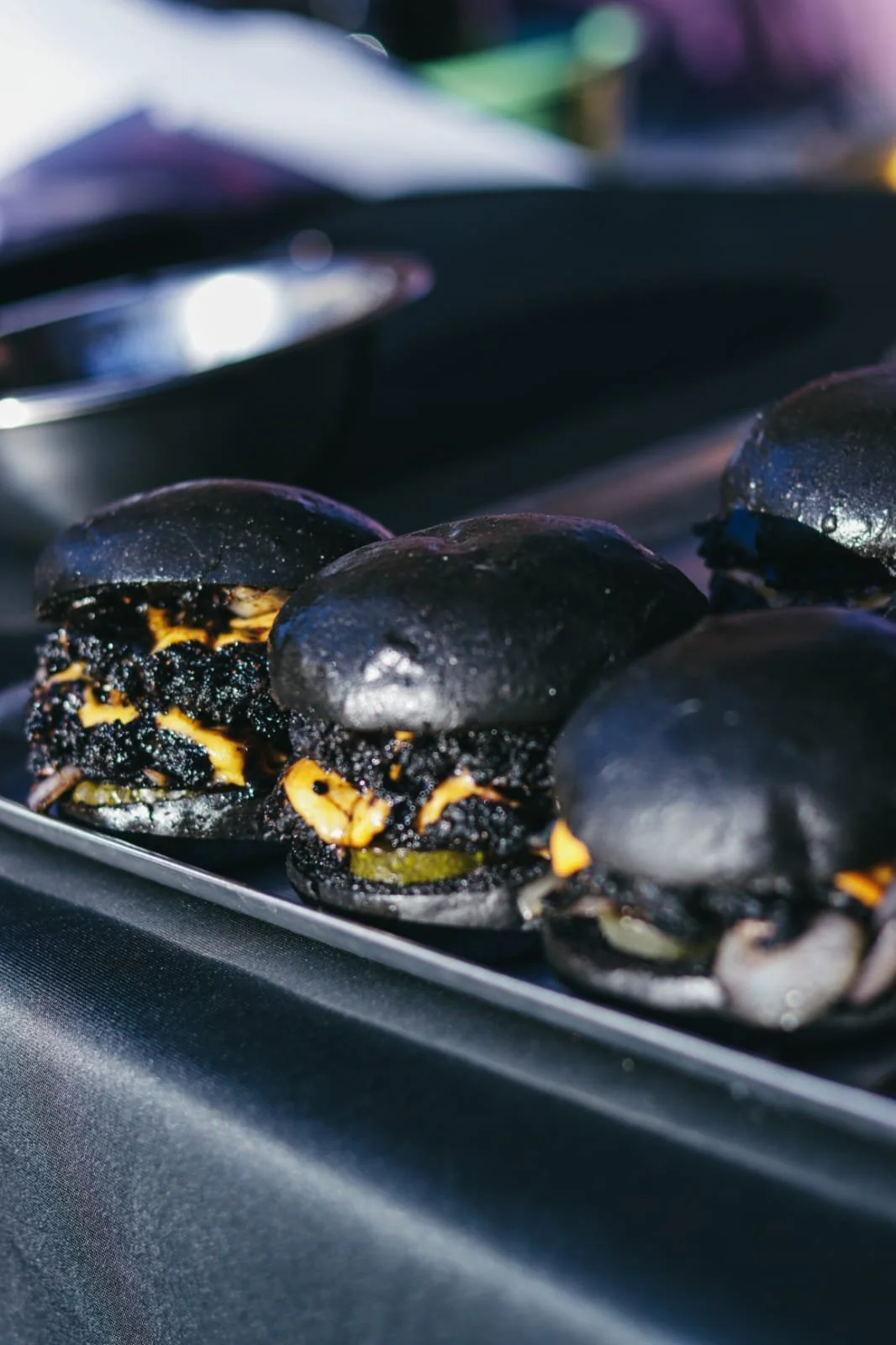 Close-up of black burgers with melted cheese on a grill.