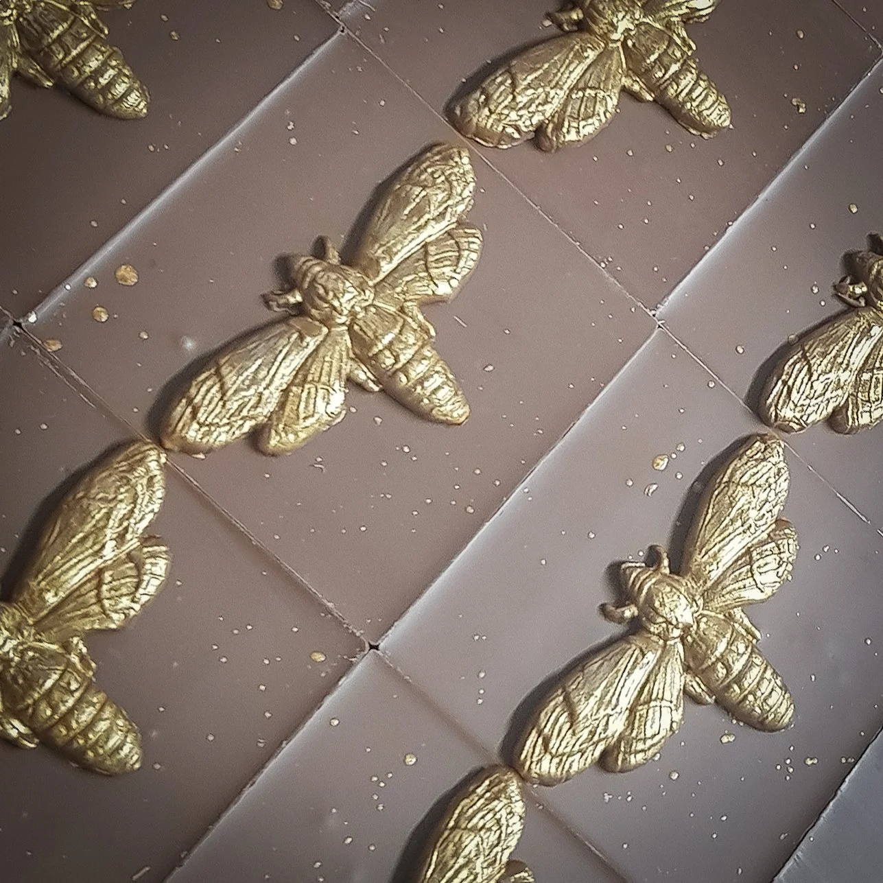 Golden decorative bees arranged in a pattern on a tiled surface.