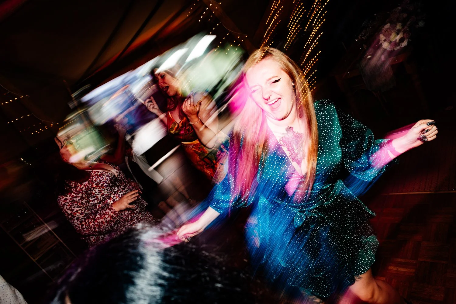 Group of women dancing and having fun at a party with colorful, blurred lights.