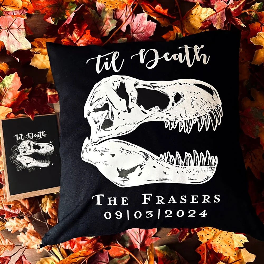 Black pillow with a white dinosaur skull illustration, surrounded by autumn leaves. Text reads 'til Death' at the top and 'The Frasers 09/03/2024' at the bottom.