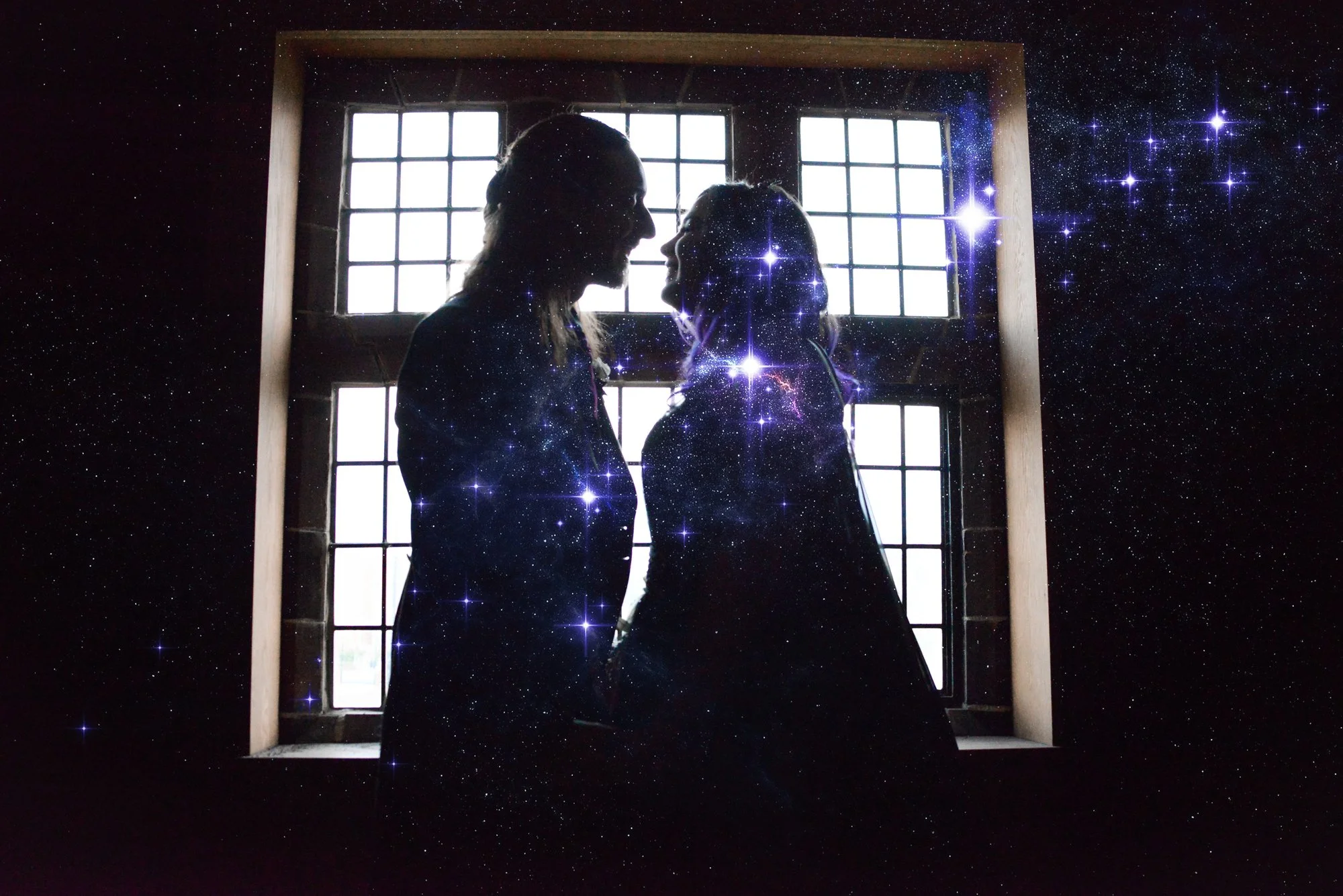 Silhouettes of two women facing each other inside a room with large grid windows, with a starry galaxy overlay.