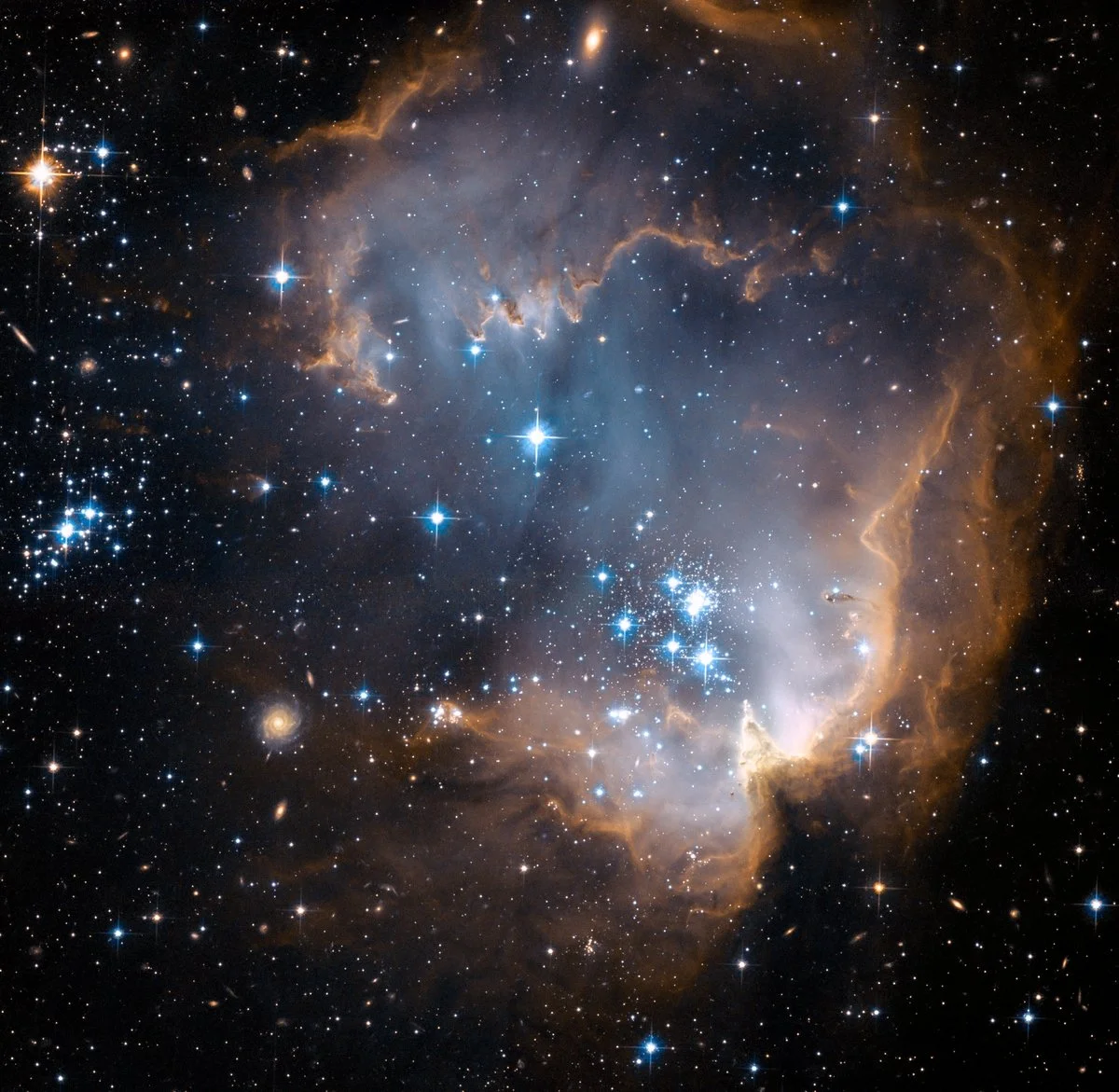 A breathtaking view of outer space featuring a nebula with orange, white, and blue hues, surrounded by numerous stars of varying brightness.