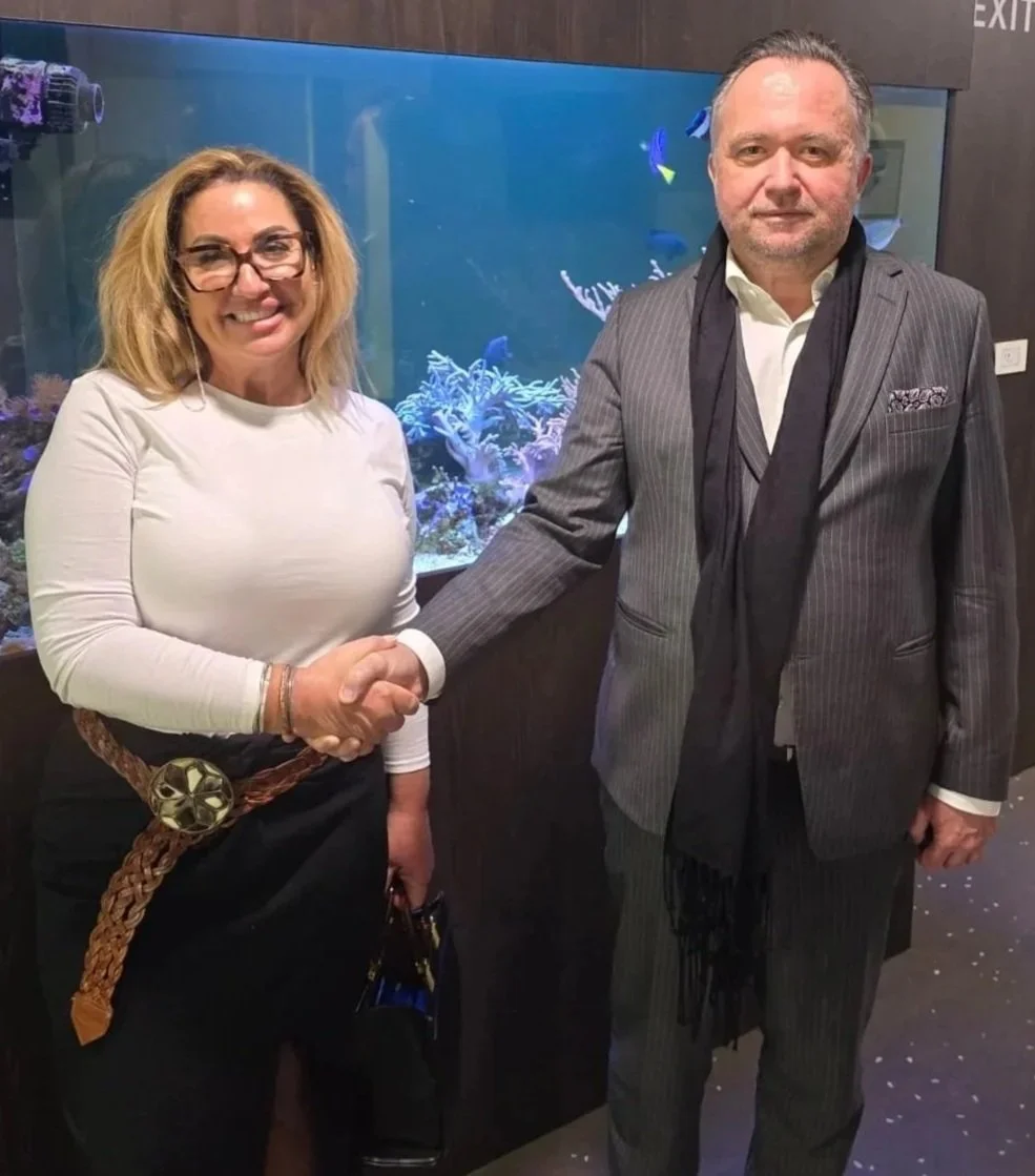Both owners of TCS and of Clinic in Croatia, woman and man shaking hands in front of an aquarium in the Clinics waiting area, both dressed smart.