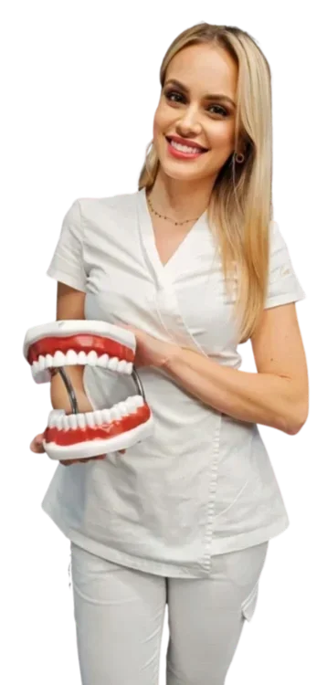 A smiling woman in medical scrubs for The Ars Salutaris clinic holding a large model of human teeth and gums.