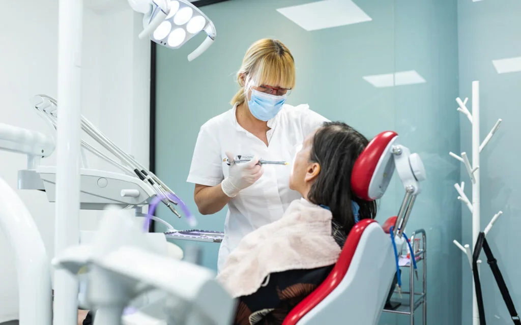Dentist wearing a mask and gloves examining a female patient's mouth in Croatian dental clinic