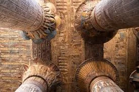 Four large stone pillars with intricate carvings, viewed from below. Egypt.