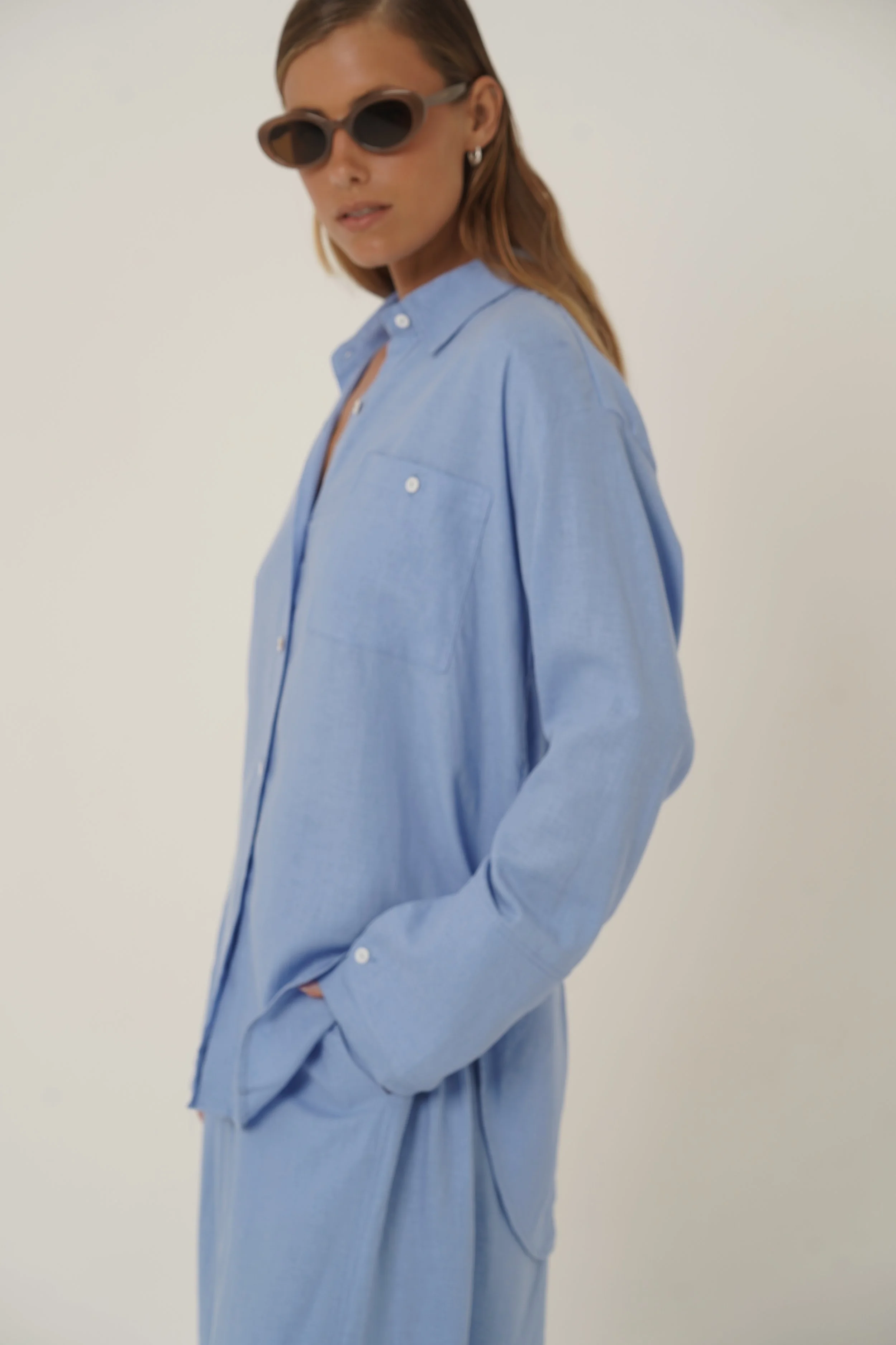 Woman wearing blue Reformation Shirt with open back and sunglasses