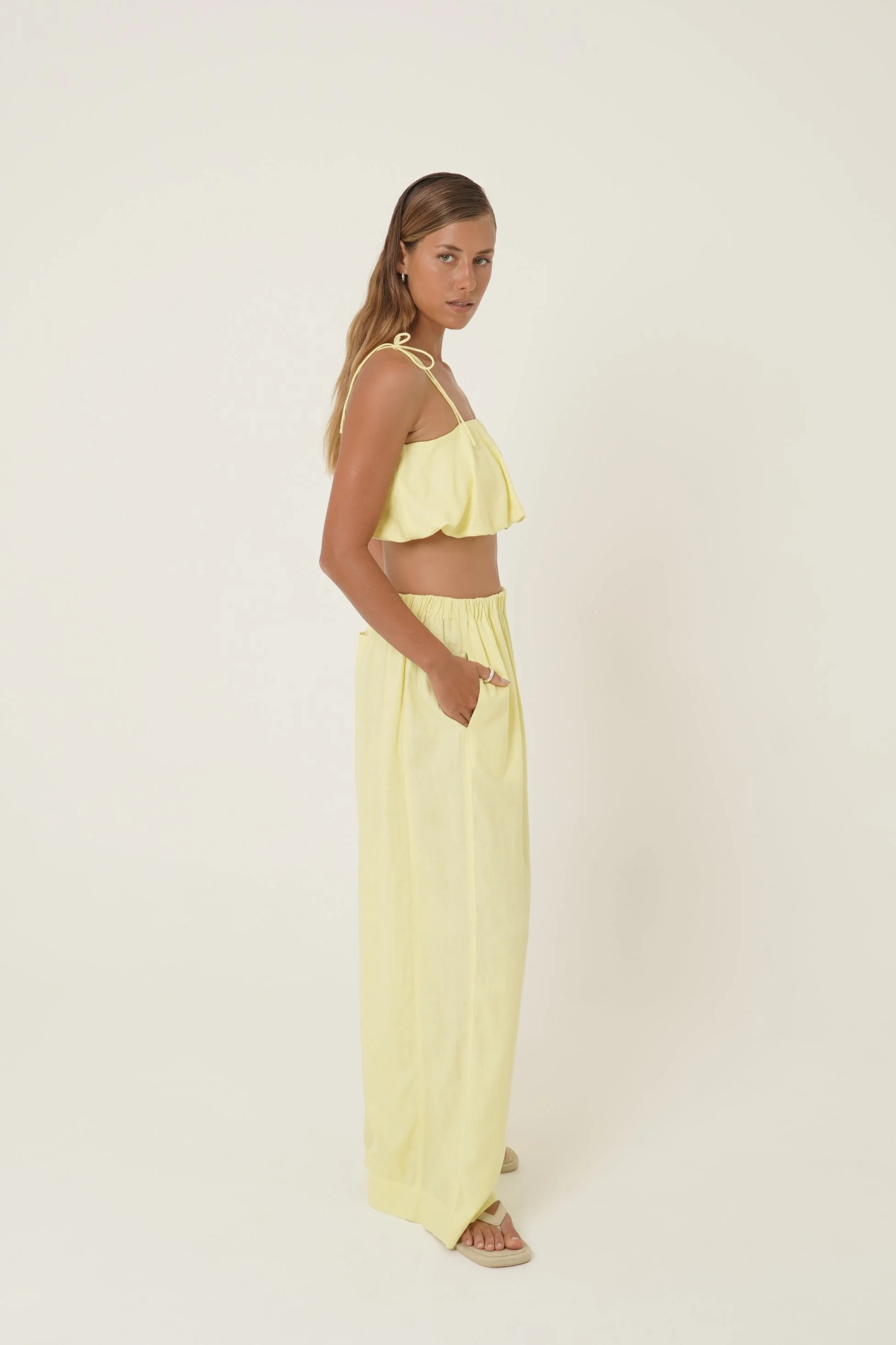 Woman wearing Crescendo Top & Bottoms in lemon colored pure linen looking sideways