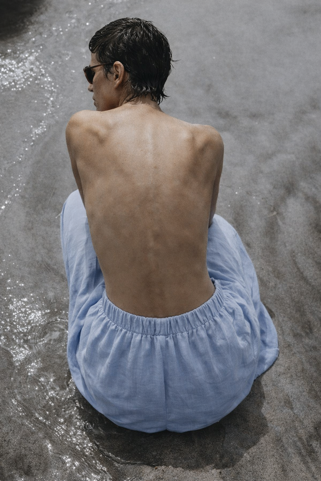 Woman sitting down on the beach wearing Crescendo Azure Blue Pants