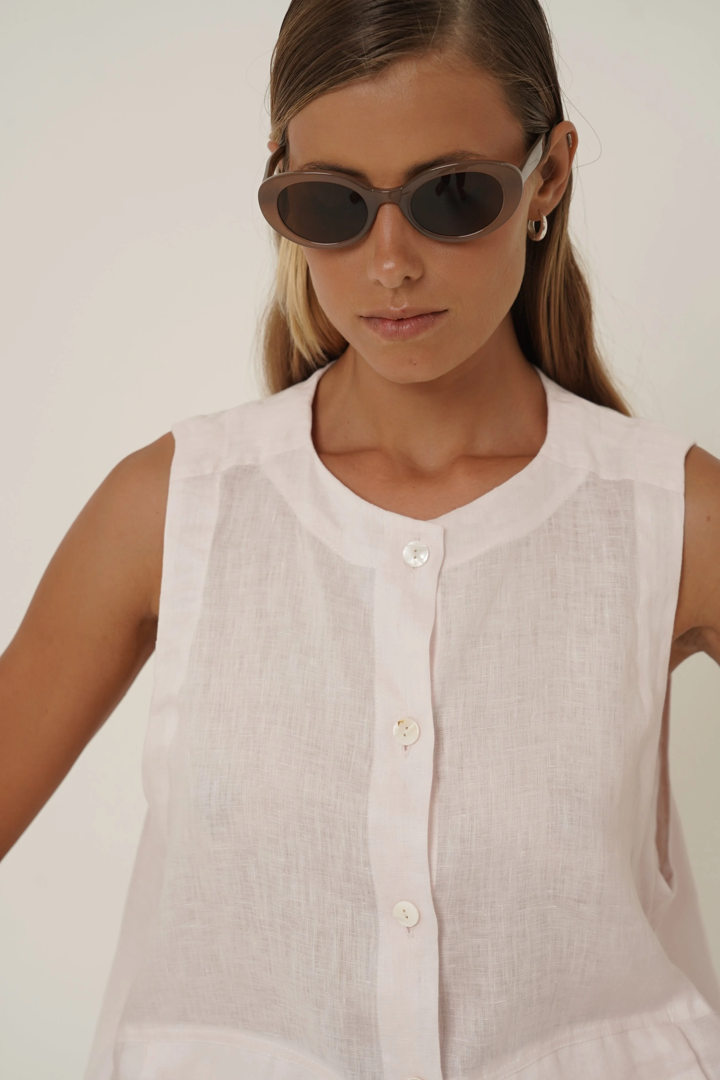 Woman wearing linen Maribou Vest with pockets, button closure and drawstring at hem with sunglasses - detail