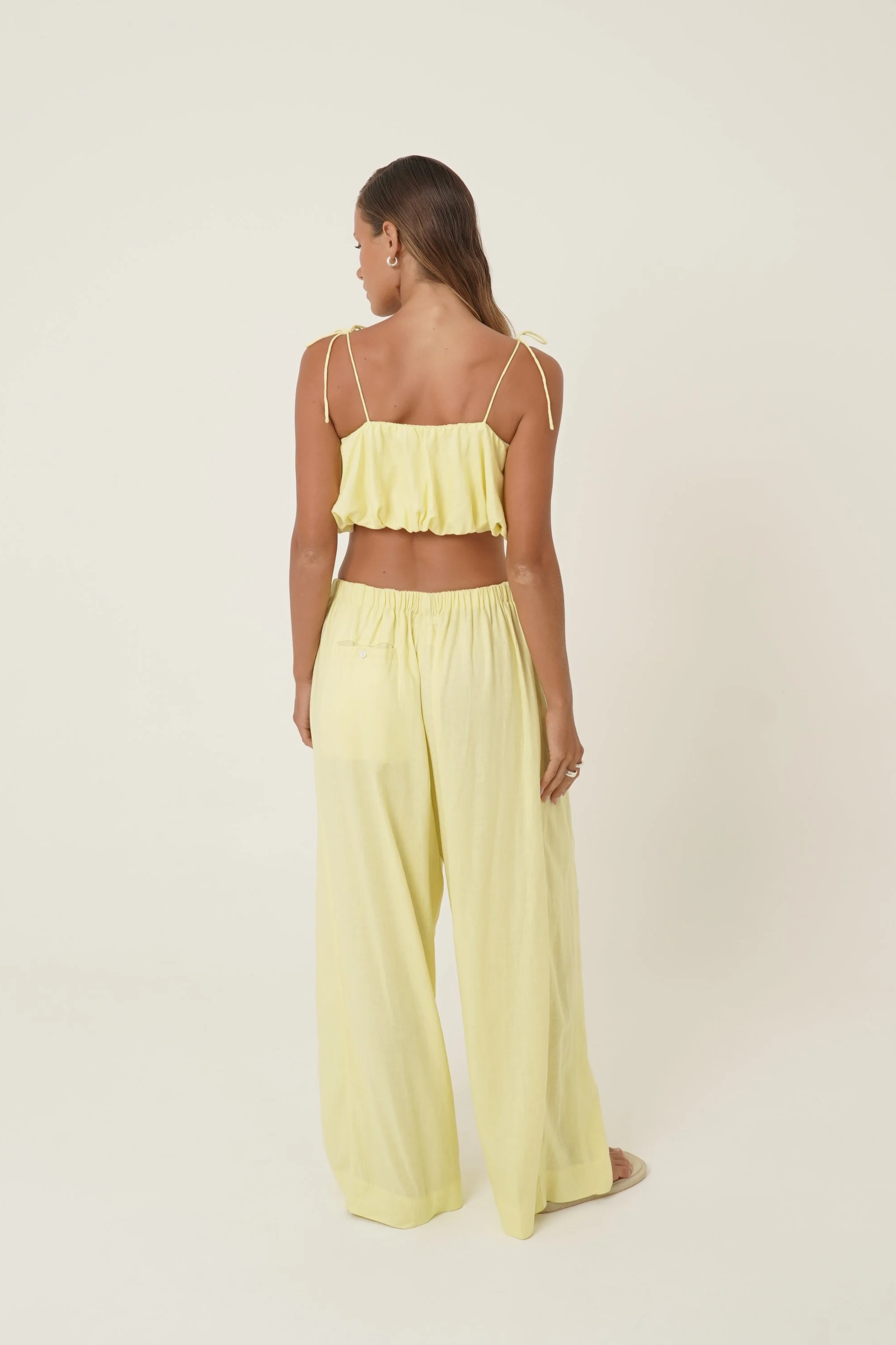 Woman wearing Crescendo Top & Bottoms in lemon colored pure linen back view