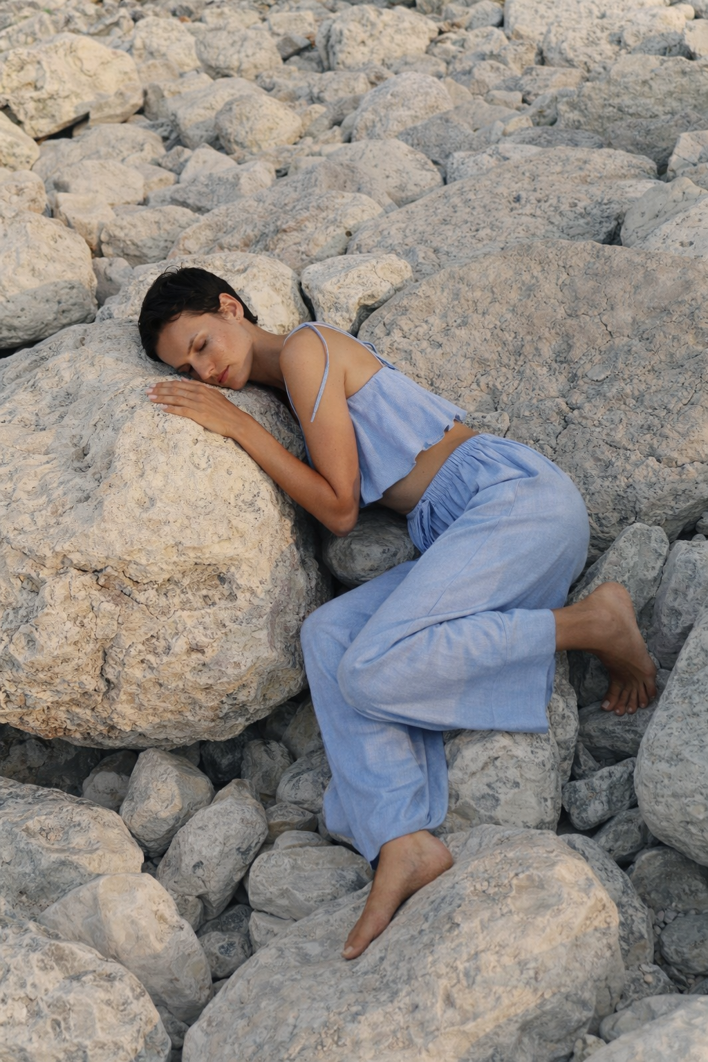 woman laying down on a rock wearing Crescendo set in Azure blue from Sutura Studio