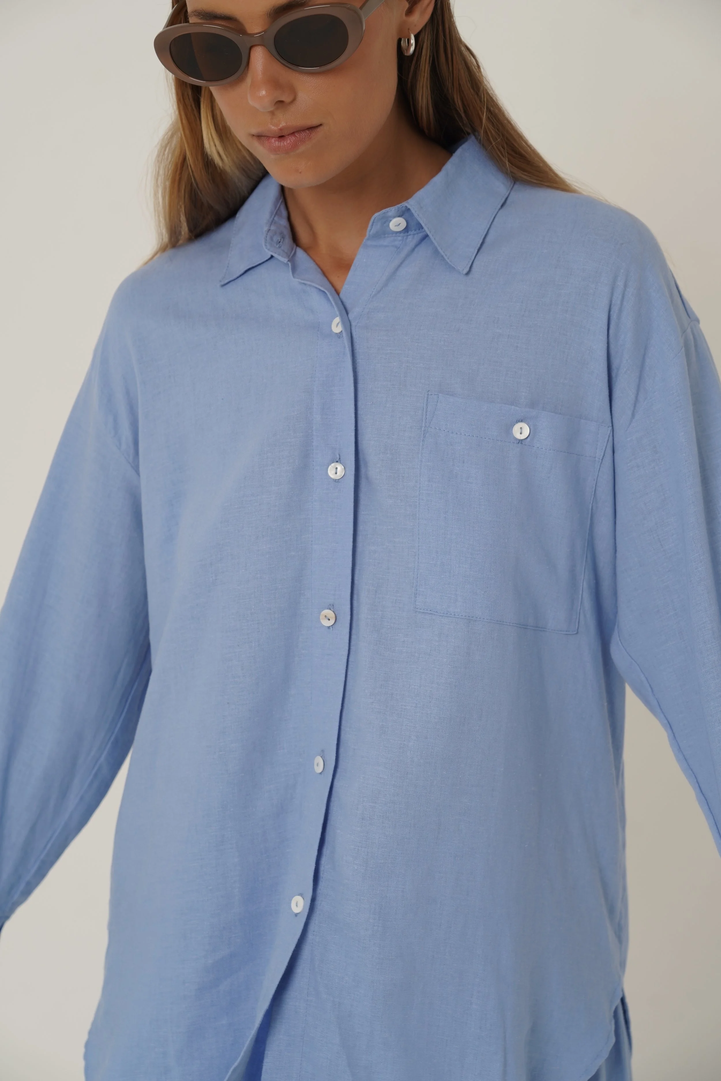 Woman wearing blue Reformation Shirt with open back and sunglasses