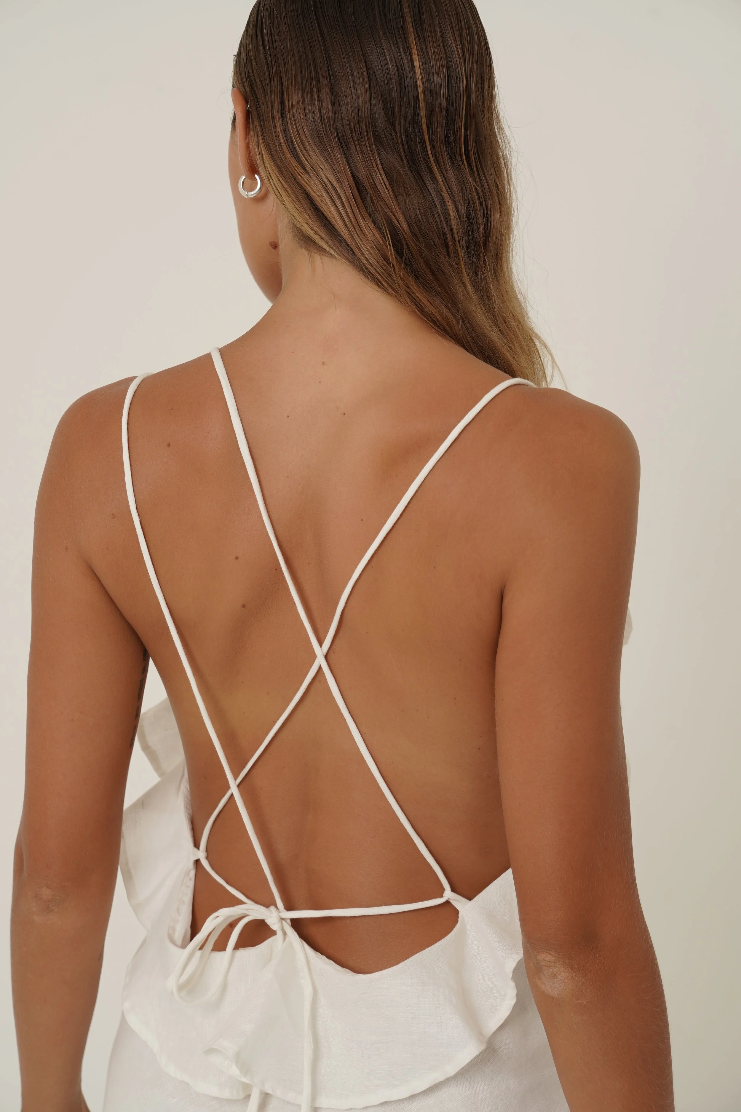 Woman wearing Renata Dress in pure white linen with back strap detail close up