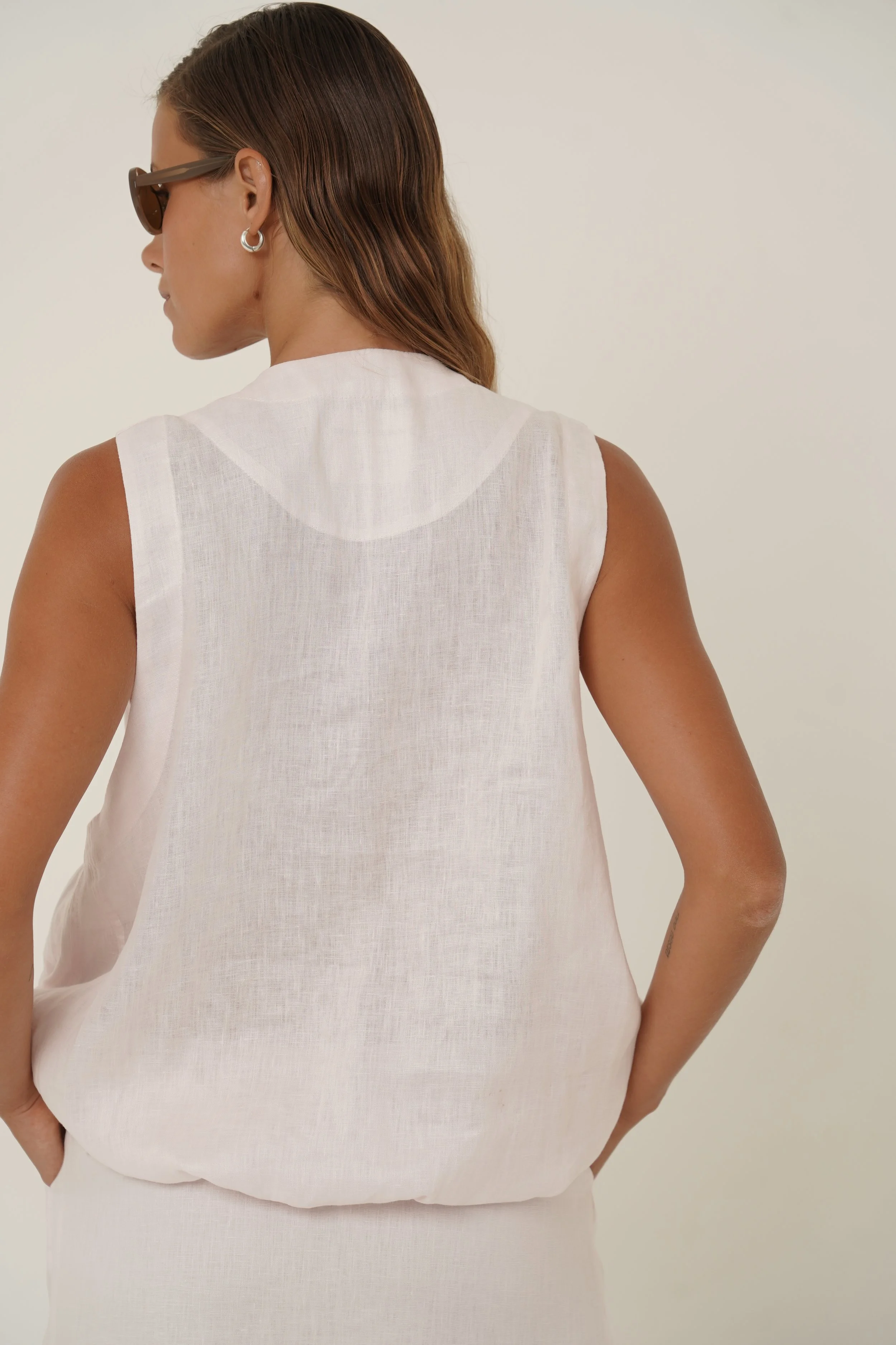 Woman wearing linen Maribou Vest with pockets, button closure and drawstring at hem - back
