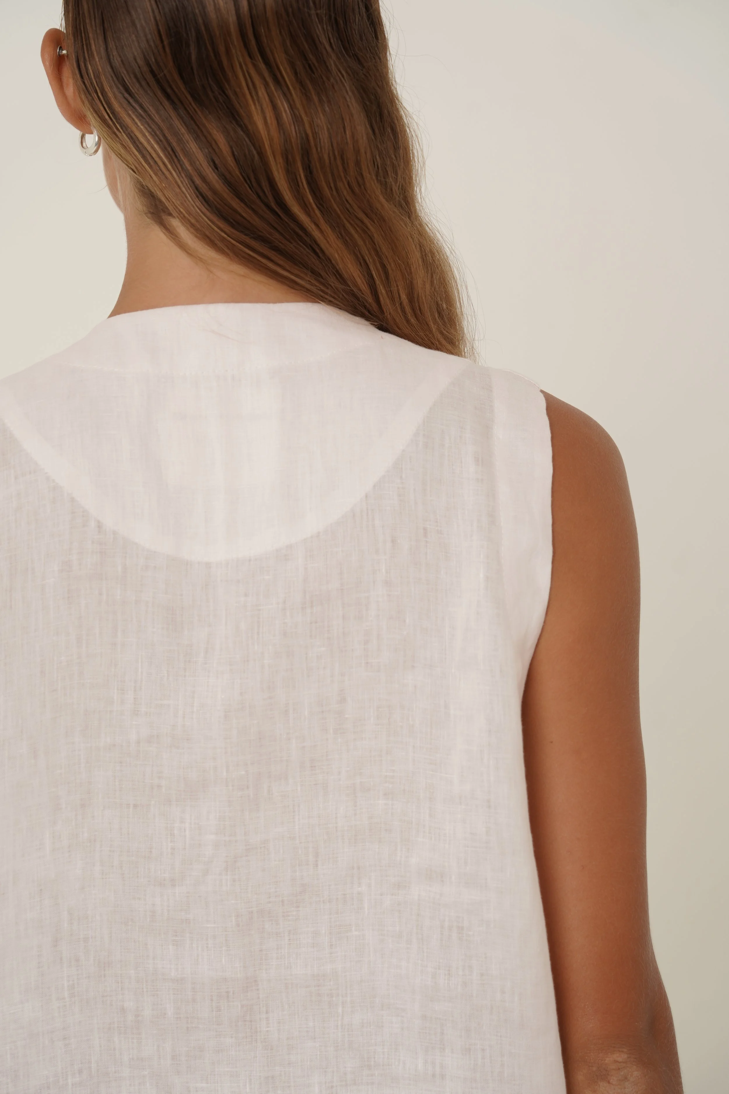 Woman wearing linen Maribou Vest with pockets, button closure and drawstring at hem - back detail