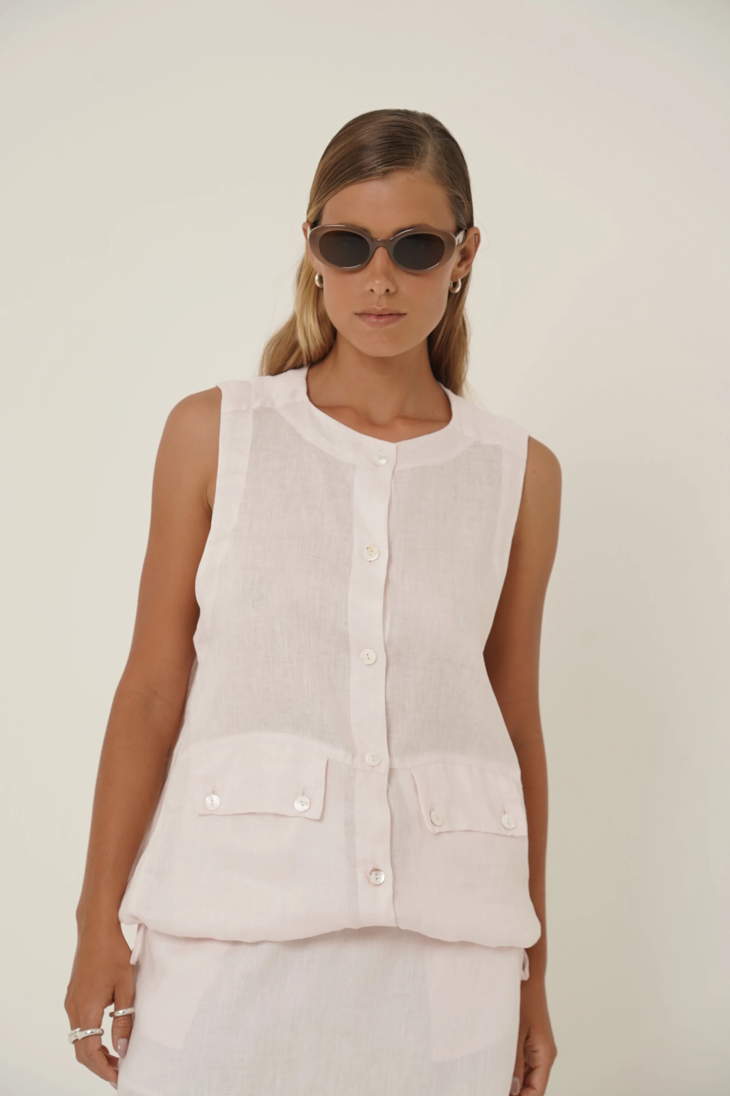 Woman wearing linen Maribou Vest with pockets, button closure and drawstring at hem - close-up