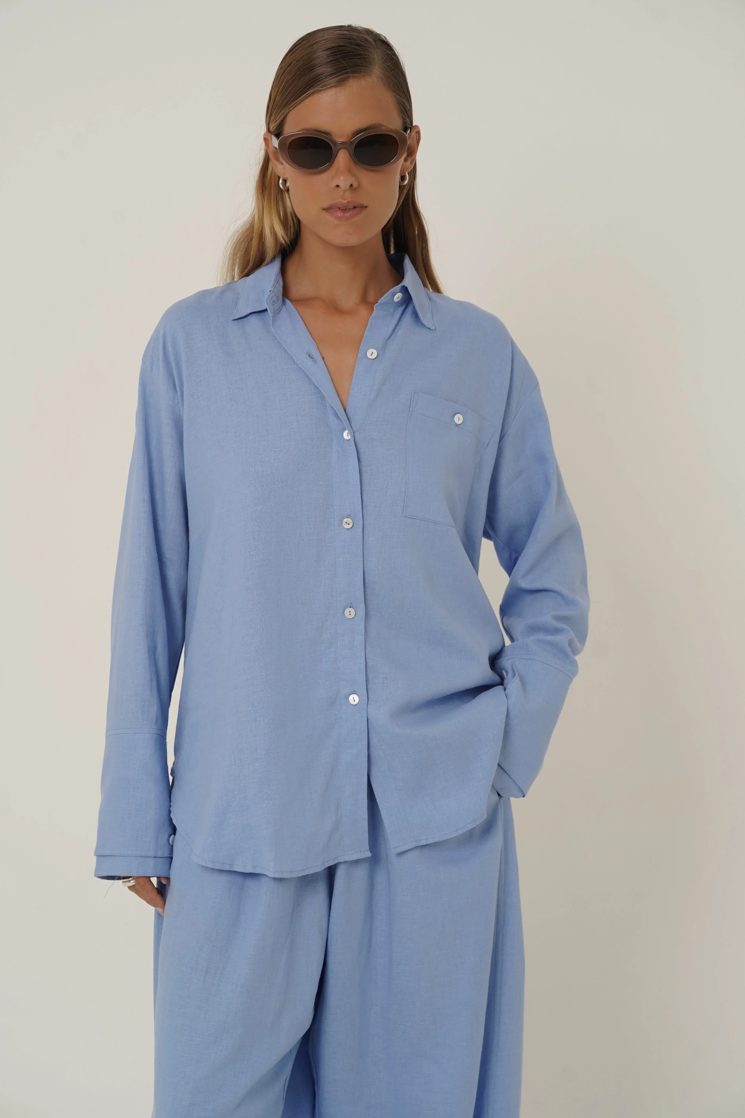 Woman wearing blue Reformation Shirt with open back and sunglasses