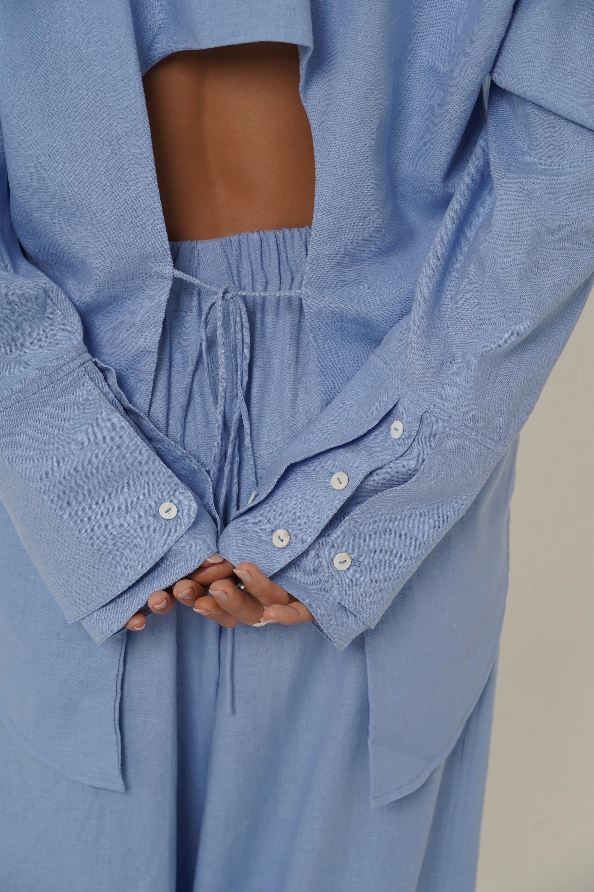 Woman wearing blue Reformation Shirt with open back and sunglasses
