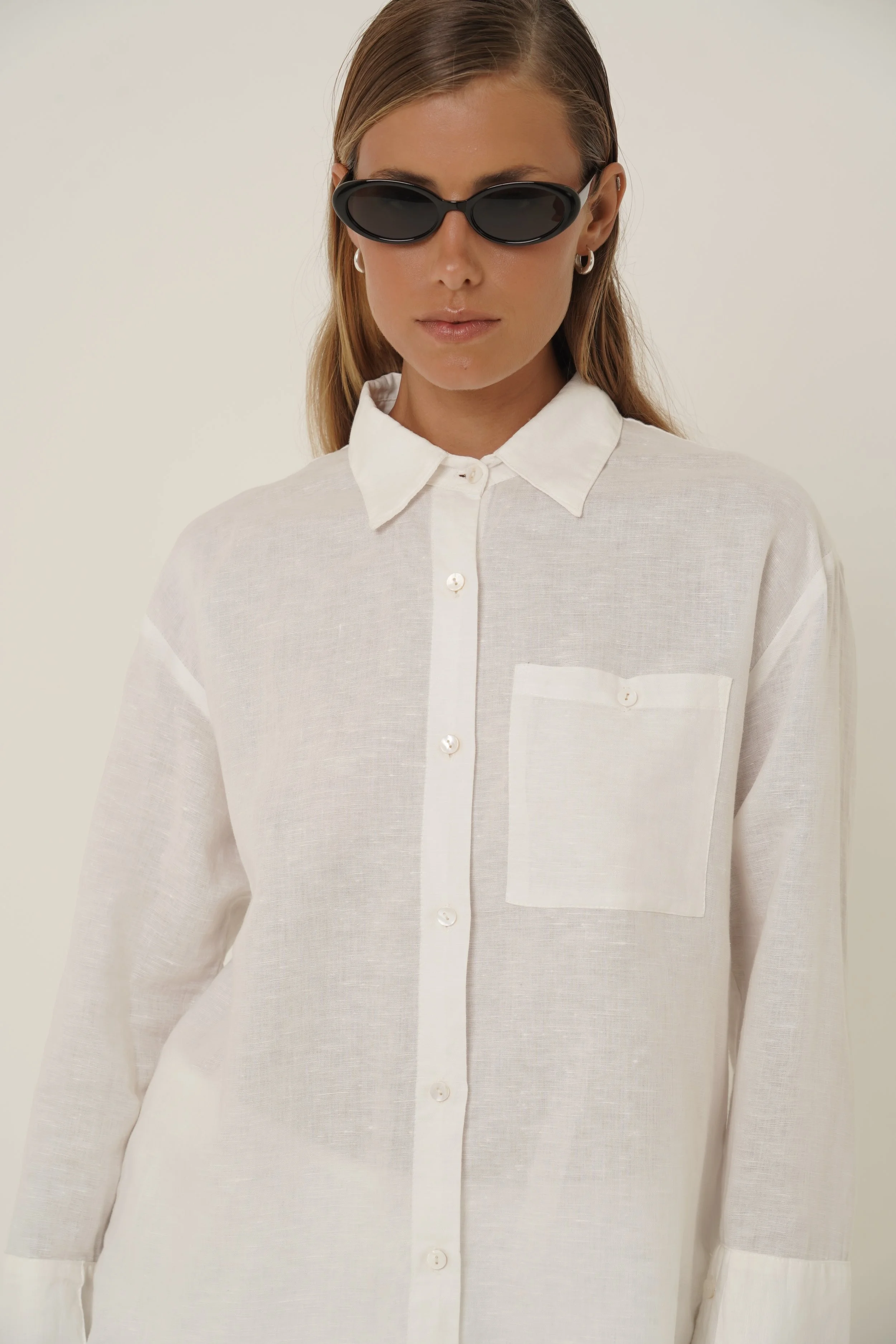 Woman wearing Reformation Shirt in white linen with sunglasses