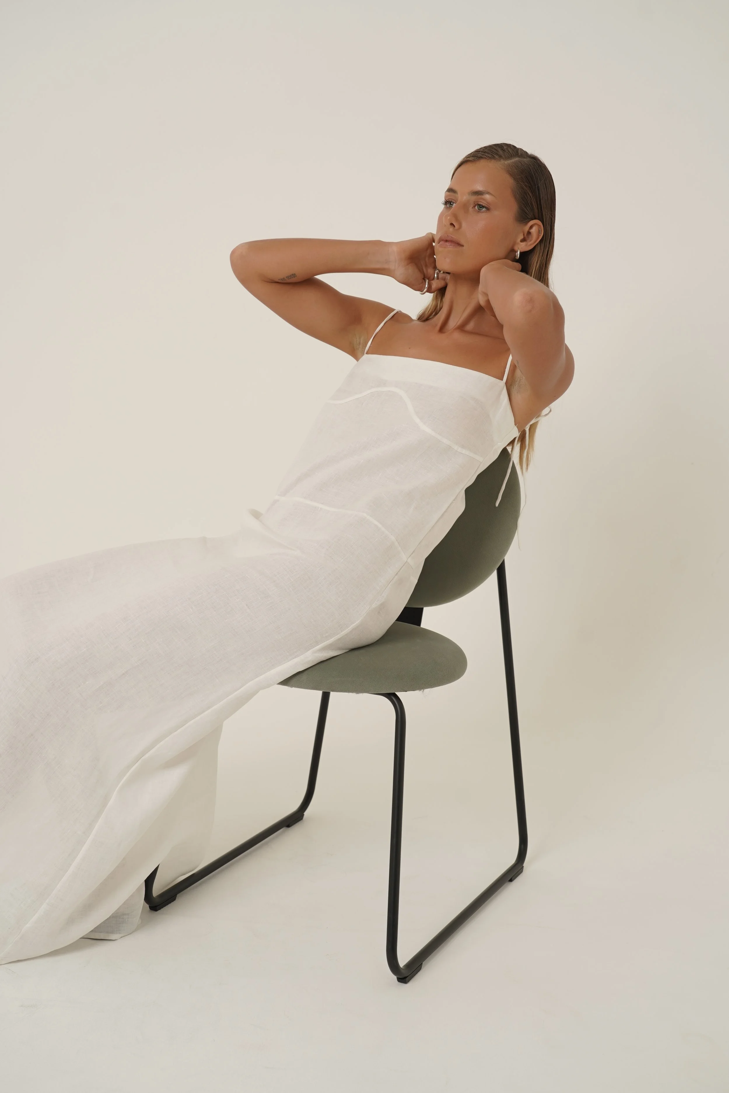 Woman wearing Prélude Maxi Dress in pure linen sitting on chair