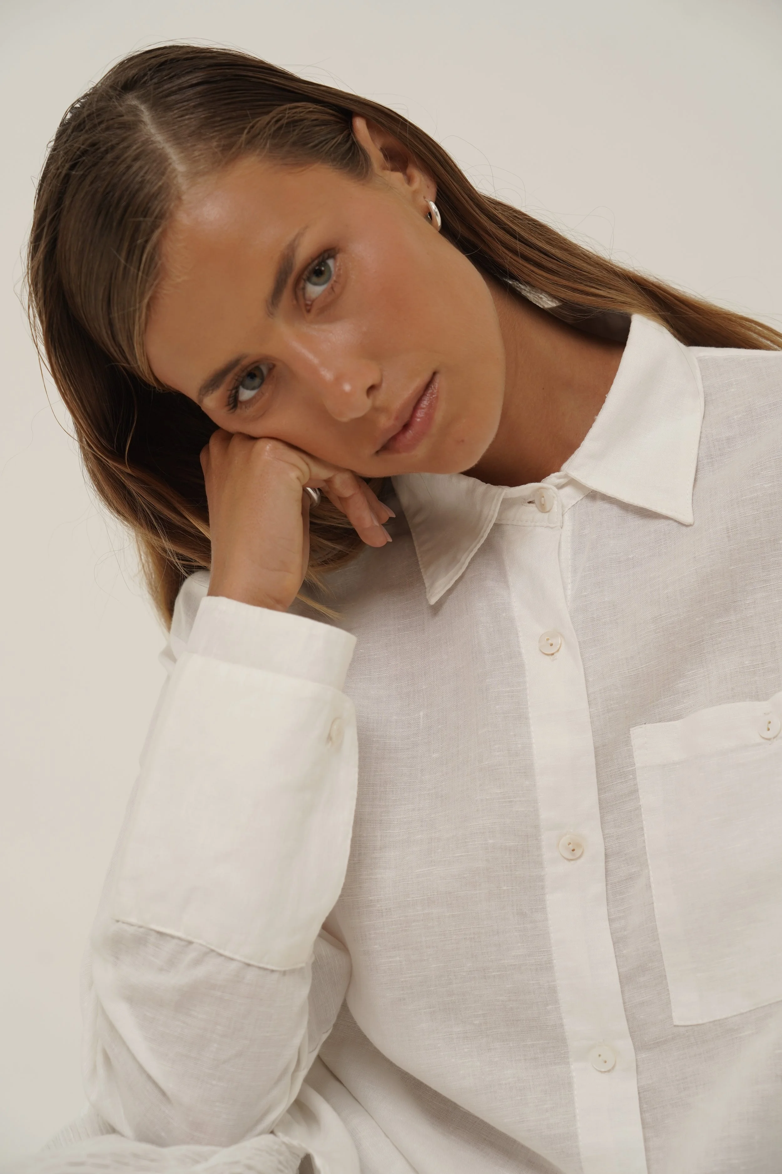 Woman leaning on hands and wearing white pure linen Reformation Shirt