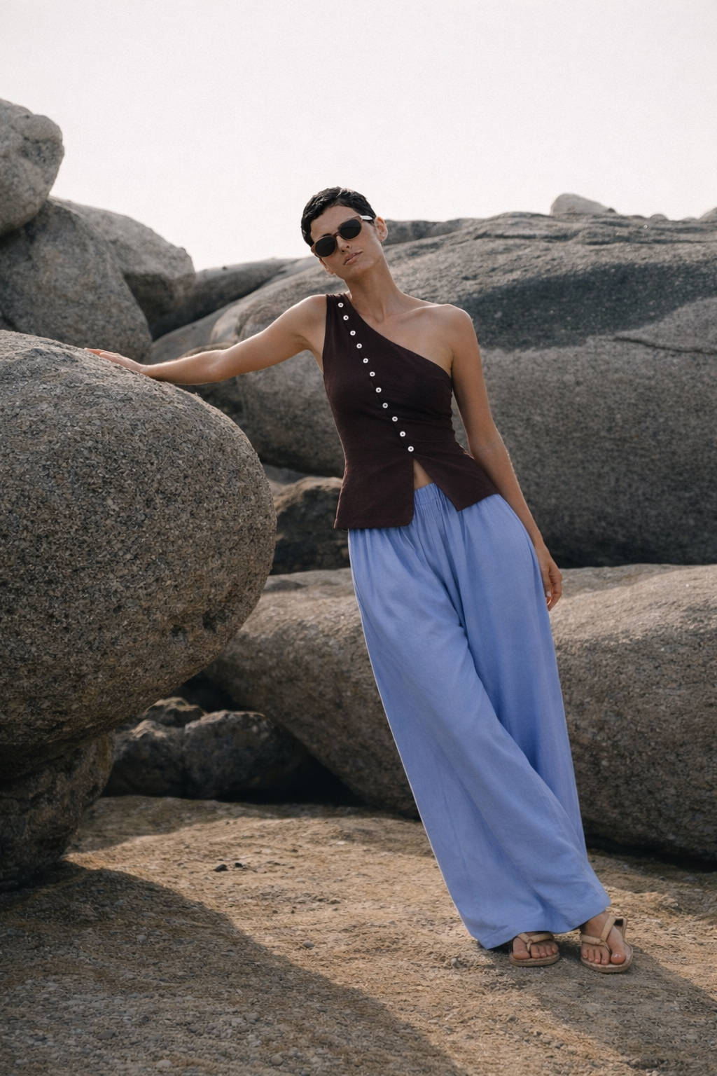 woman leaning against rock on beach wearing Sriani Top and CrescendoPants