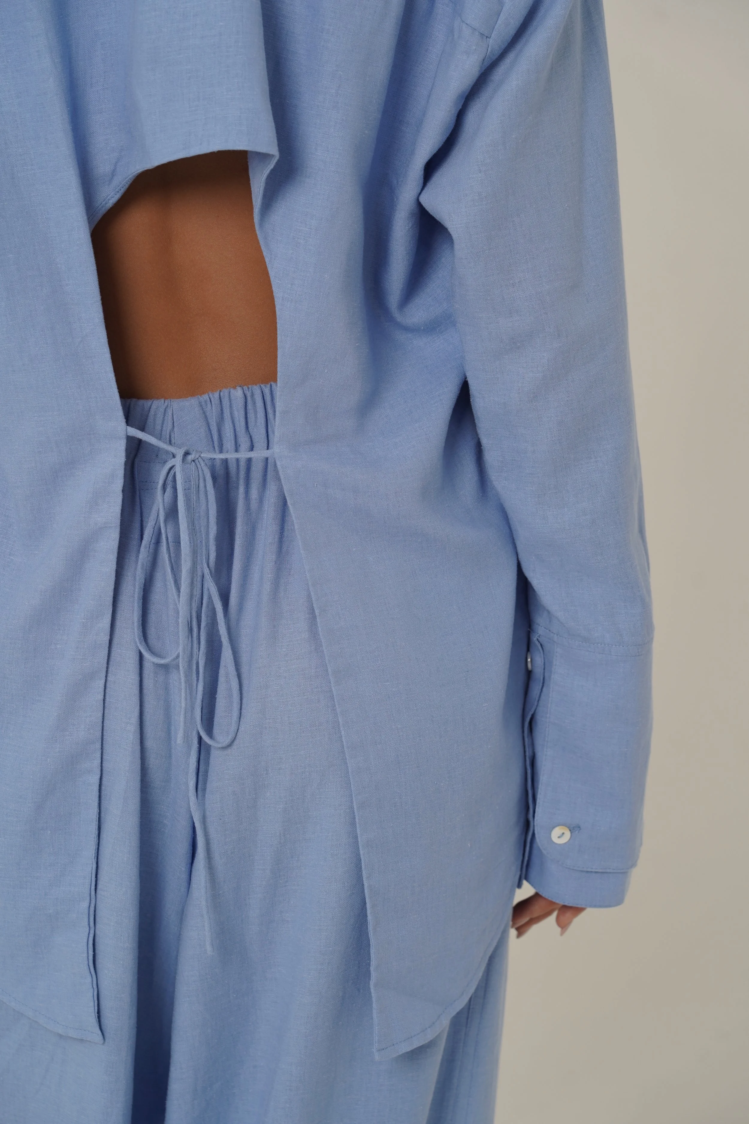 Woman wearing blue Reformation Shirt with open back and sunglasses