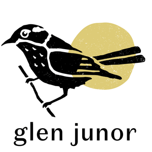 Black and white illustration of a bird perched on a branch with a yellow sun in the background and the text 'glen junor' below.