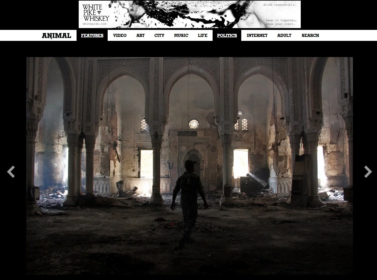 Interior of a damaged, abandoned building with Islamic architectural features, including arches and intricate designs, with debris on the floor and sunlight streaming through broken windows.
